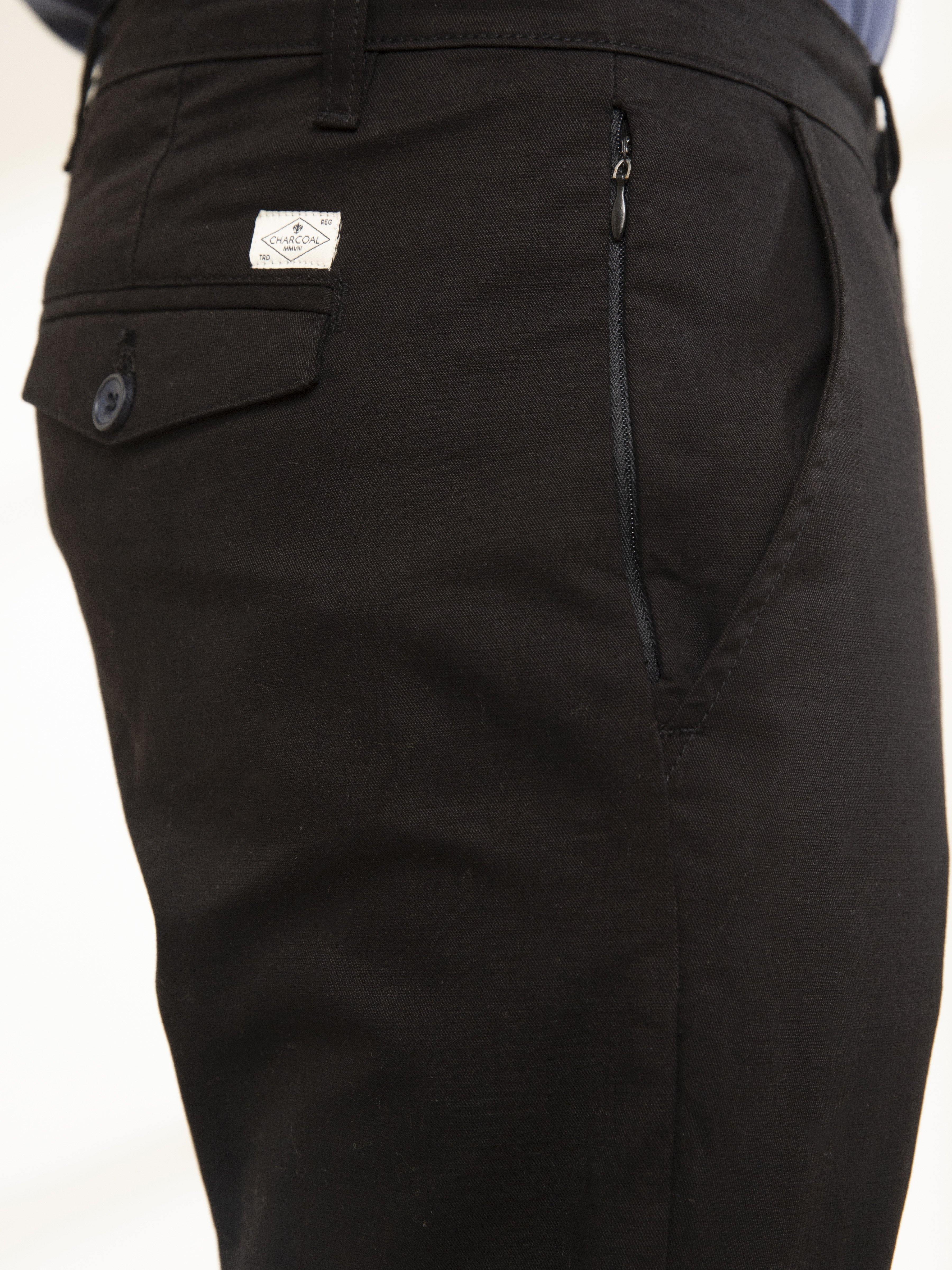 Black casual pants close-up with zip pocket and logo patch