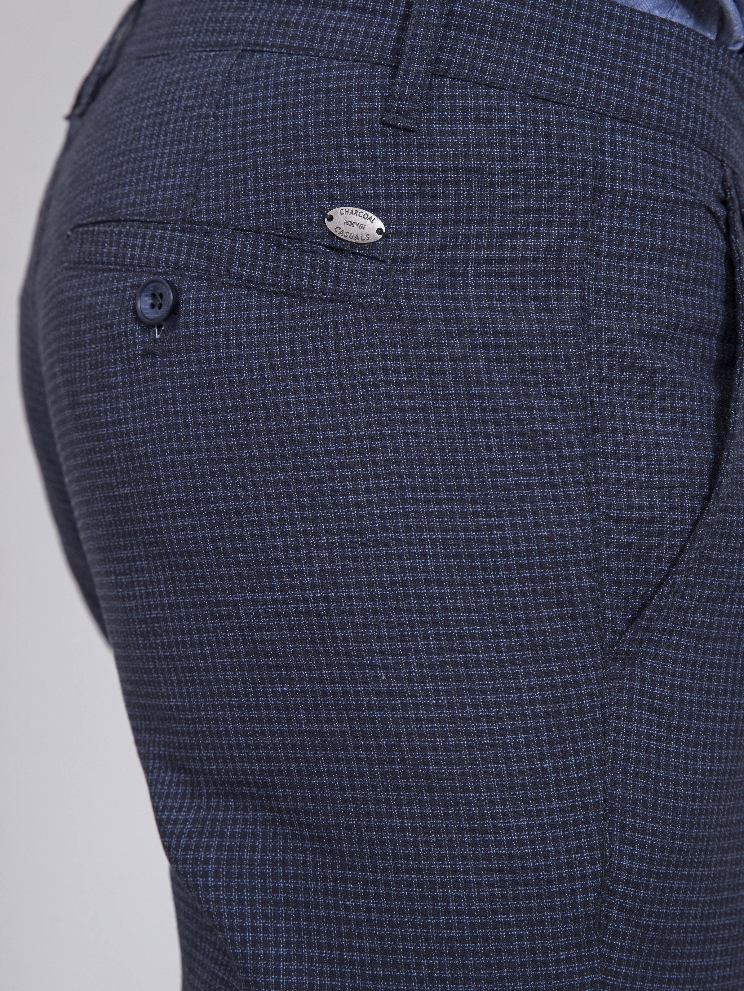 Slim-fit casual pants closeup: dark navy check back pocket with small logo patch