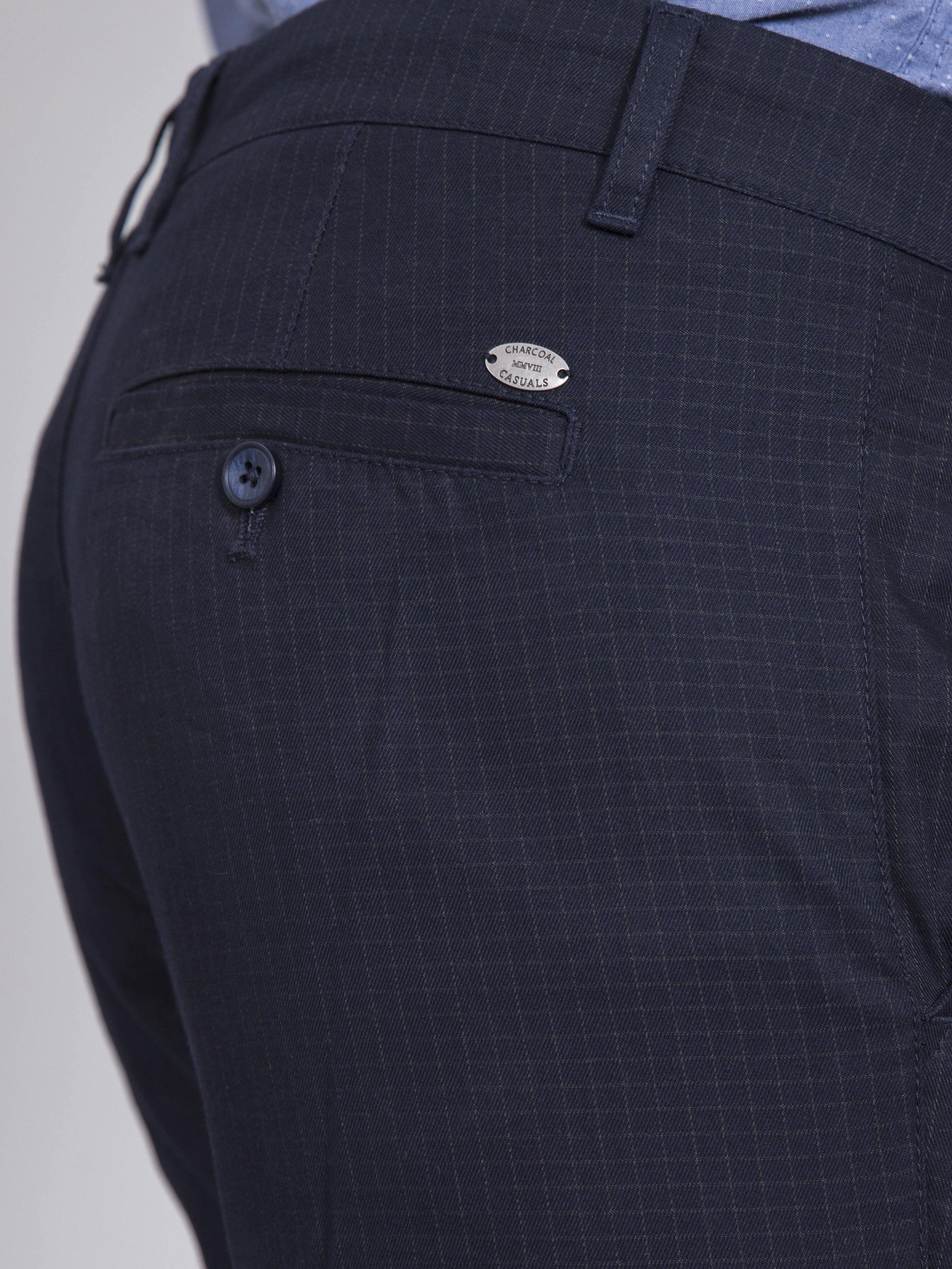 Navy casual pants close-up of back pocket with small logo patch.