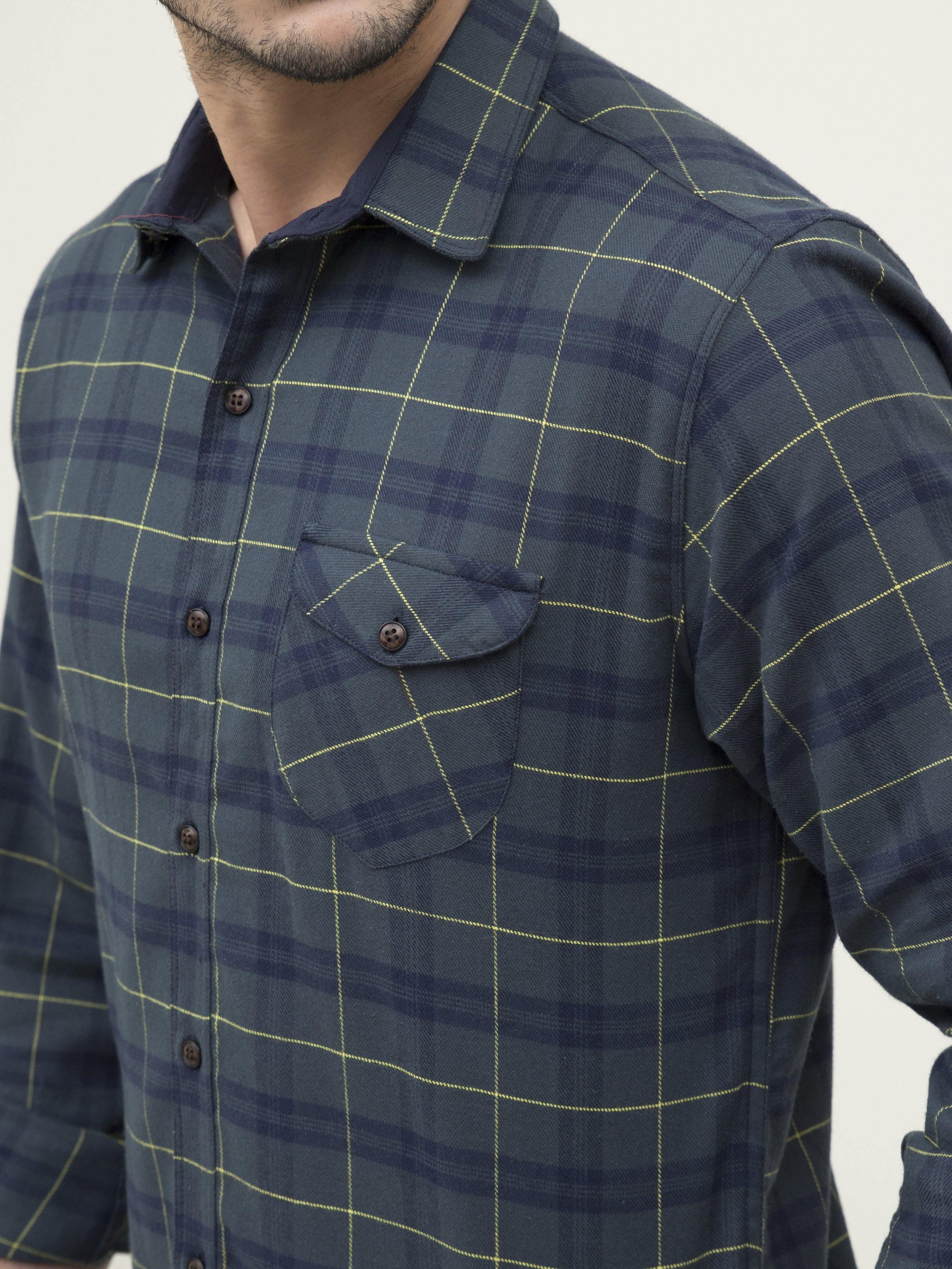 Men's plaid shirt close-up: dark blue with green grid lines, buttoned collar