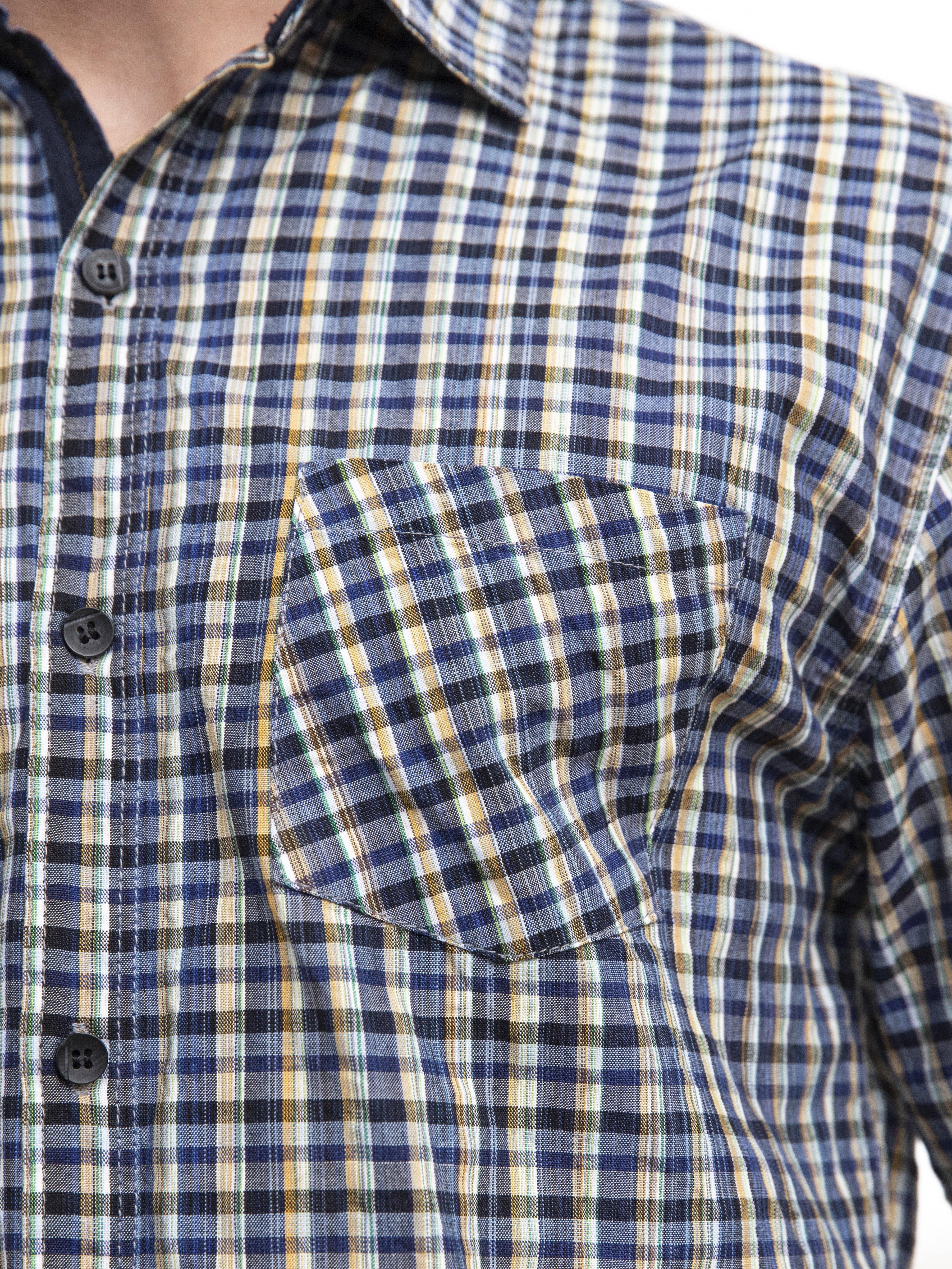 Navy-and-white check shirt close-up: chest pocket with button and placket.