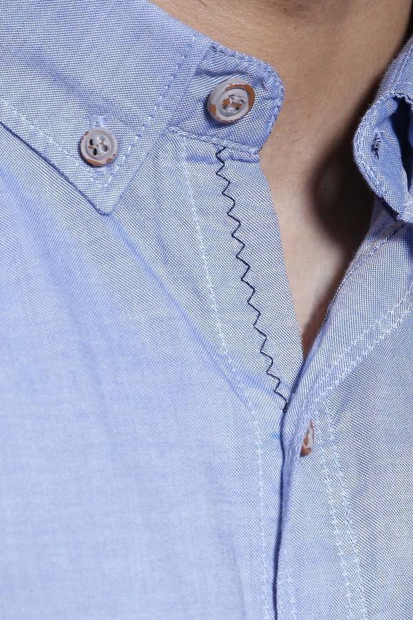 Sky blue shirt detail: buttoned placket, textured collar, and open neck