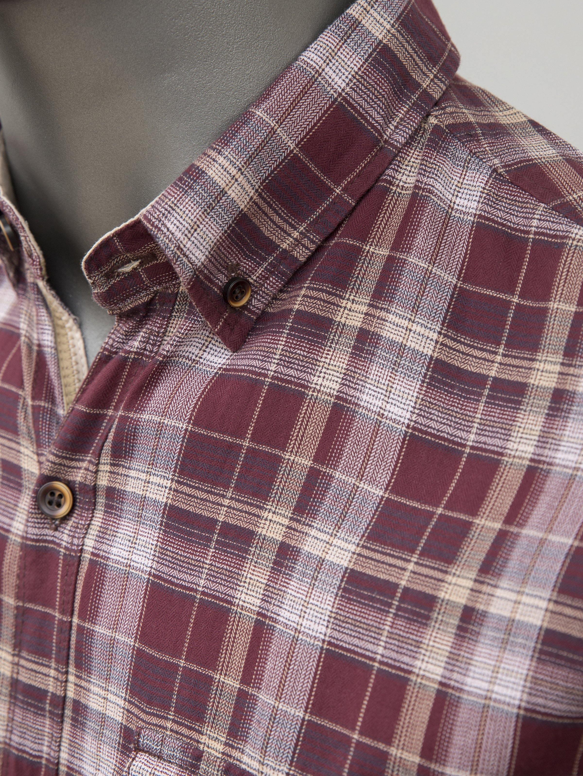 Maroon plaid button-up shirt collar detail with long sleeves and round buttons