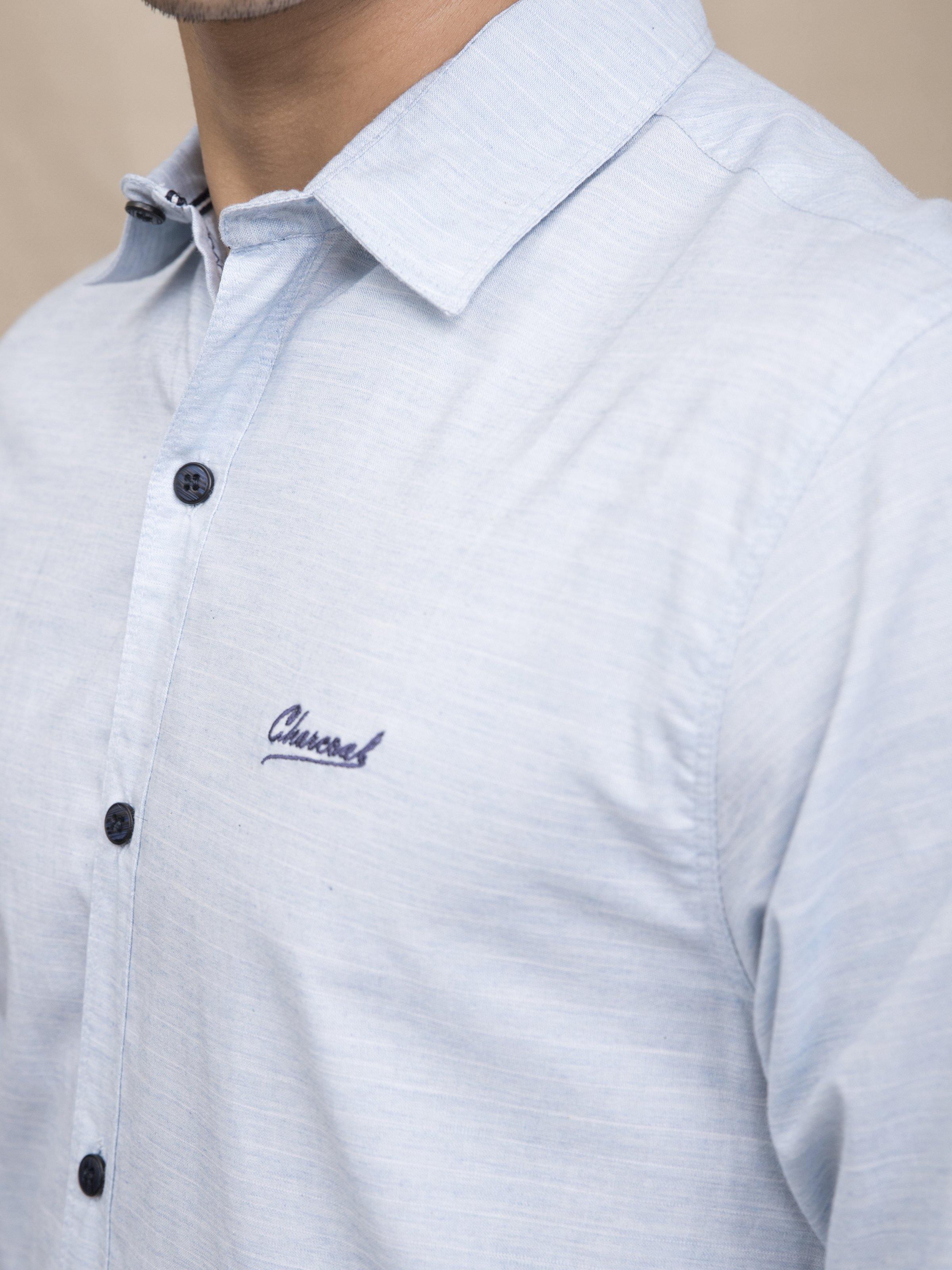 Sky blue casual button-up shirt close-up, collar, dark buttons, and chest logo