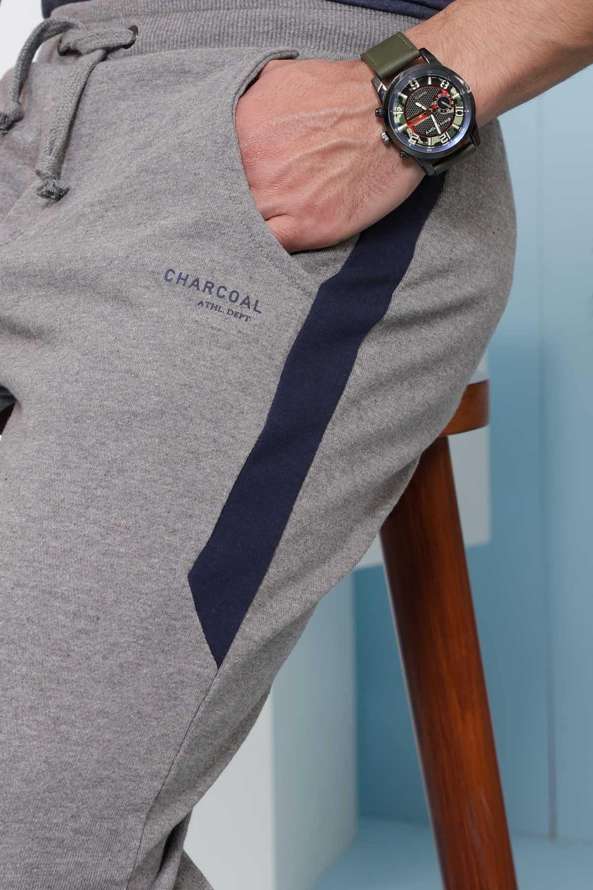 Charcoal grey jogger trousers close-up with drawcord and printed text on thigh