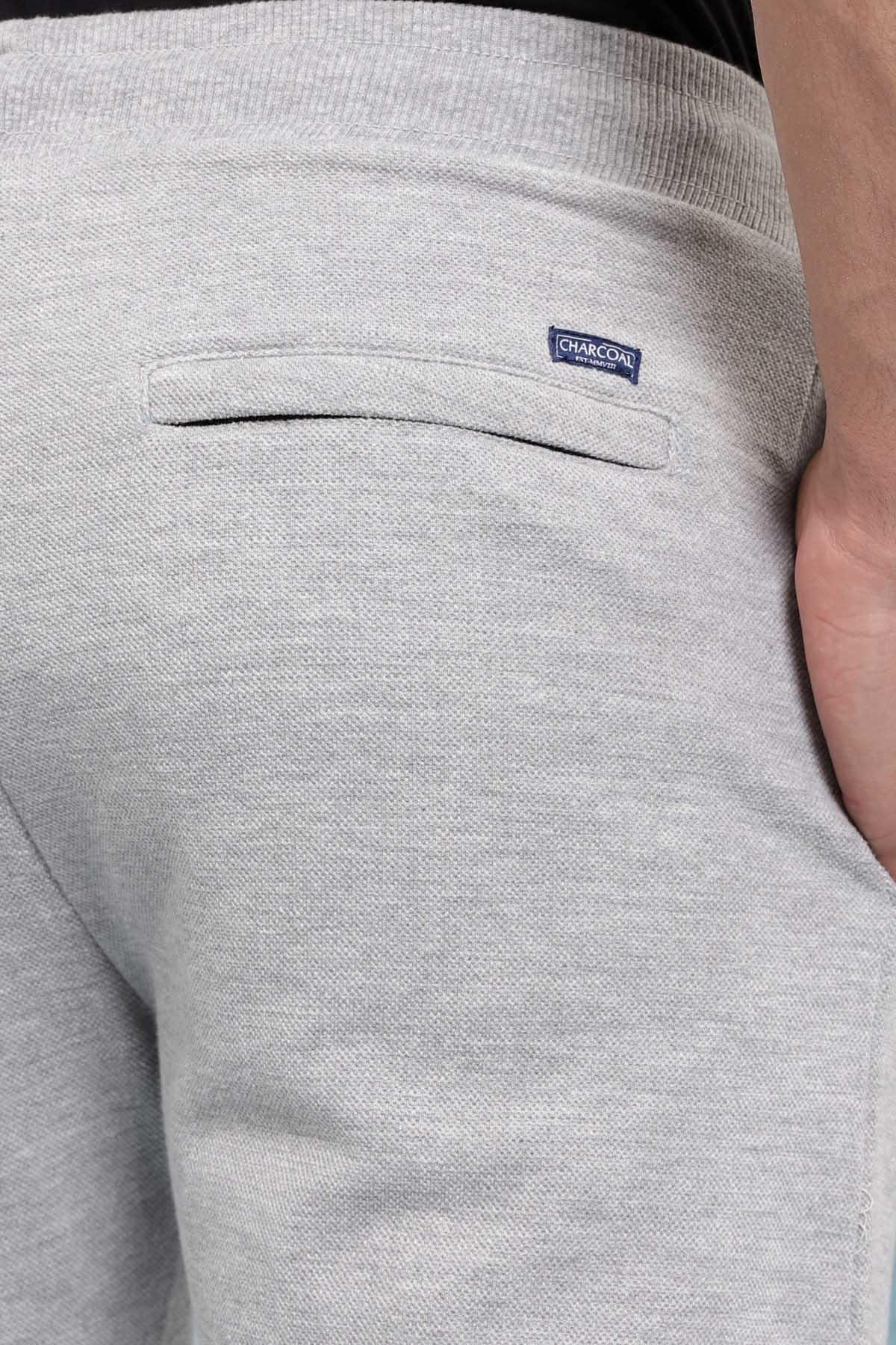 Grey casual trouser fabric close-up with stitched back pocket and logo patch