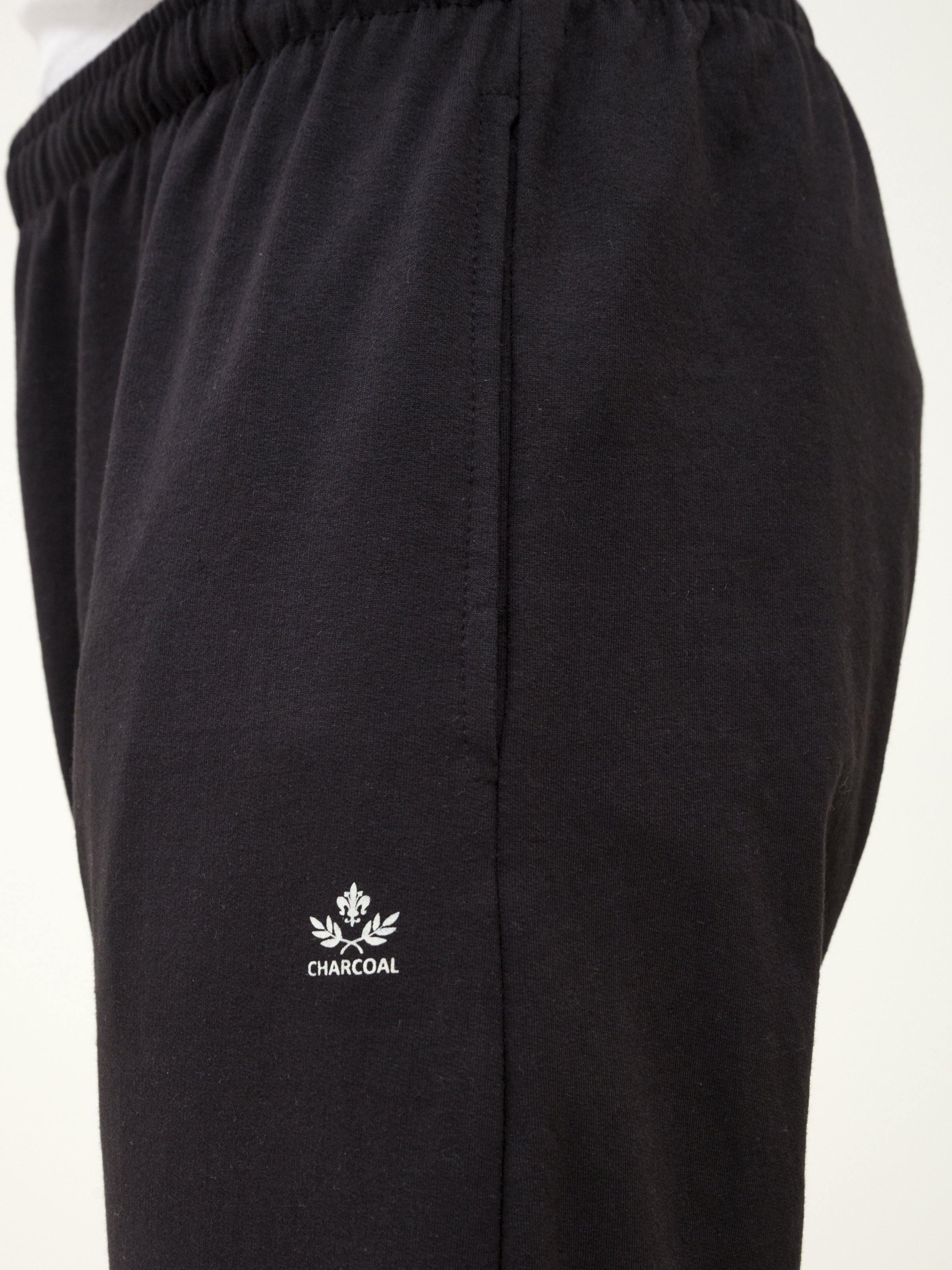 Black knit trousers close-up of elastic waistband and front logo patch