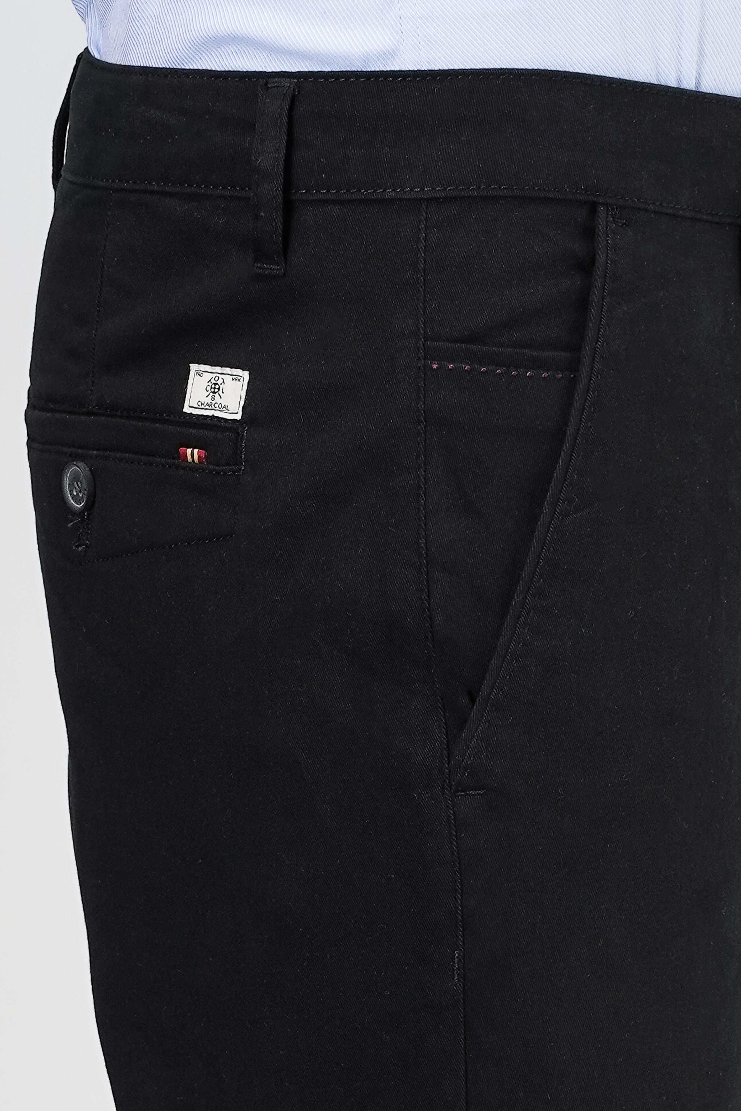Black casual pants close-up of front pocket and stitched logo patch