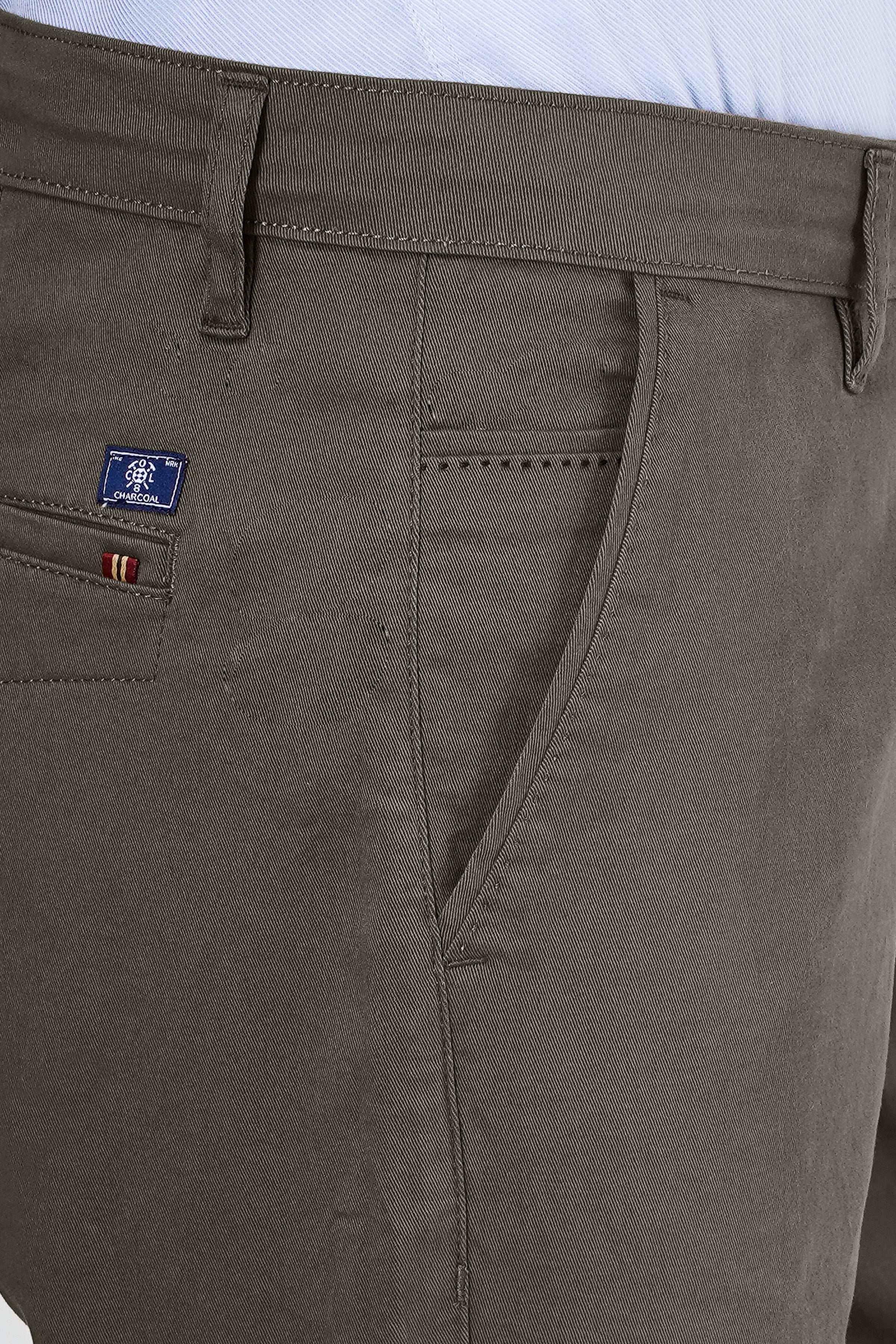 Dark olive pants pocket close-up with embroidered patch and stitched seam