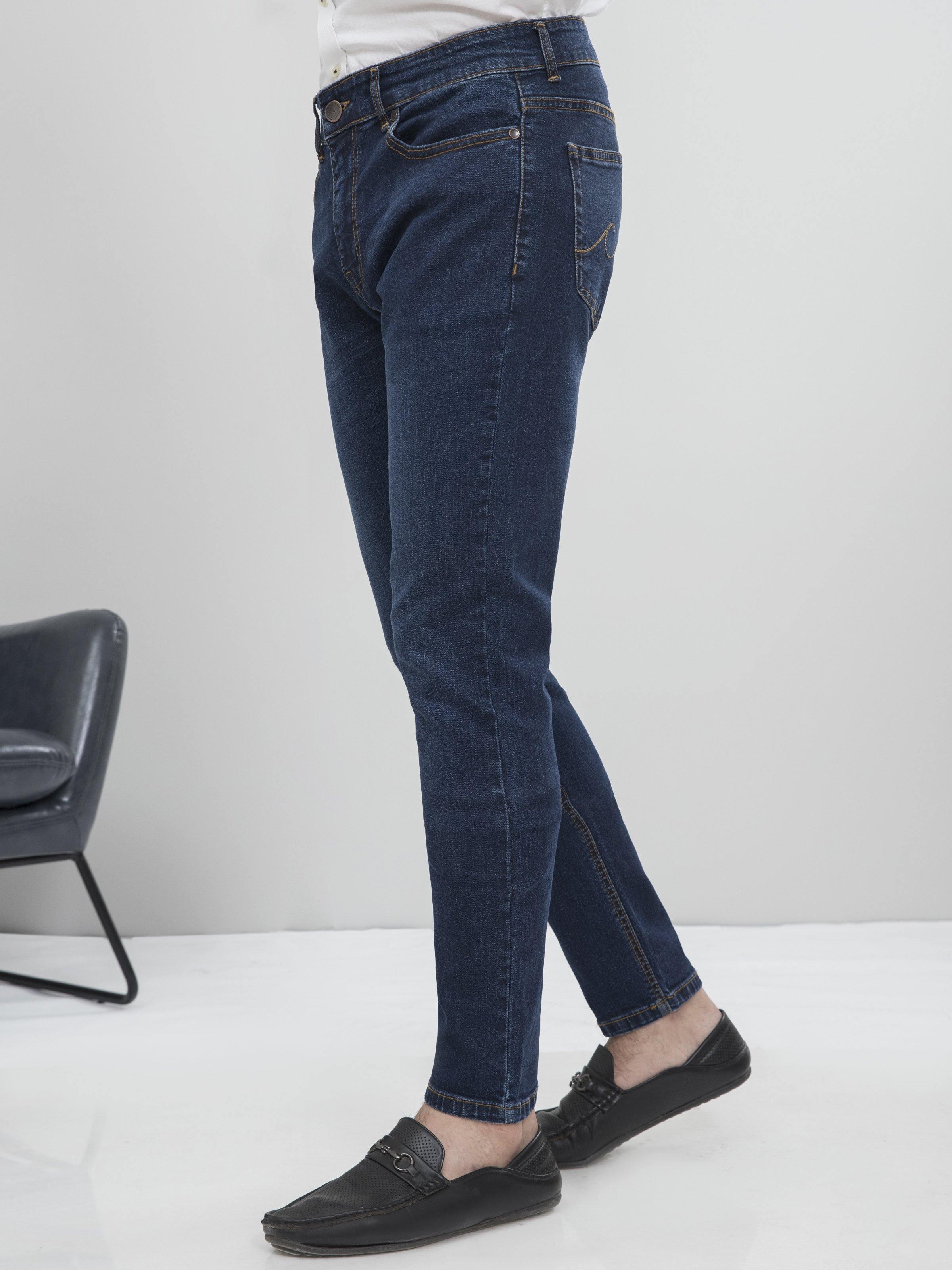 Dark blue slim-fit jeans side view with tapered leg and cuffed hem