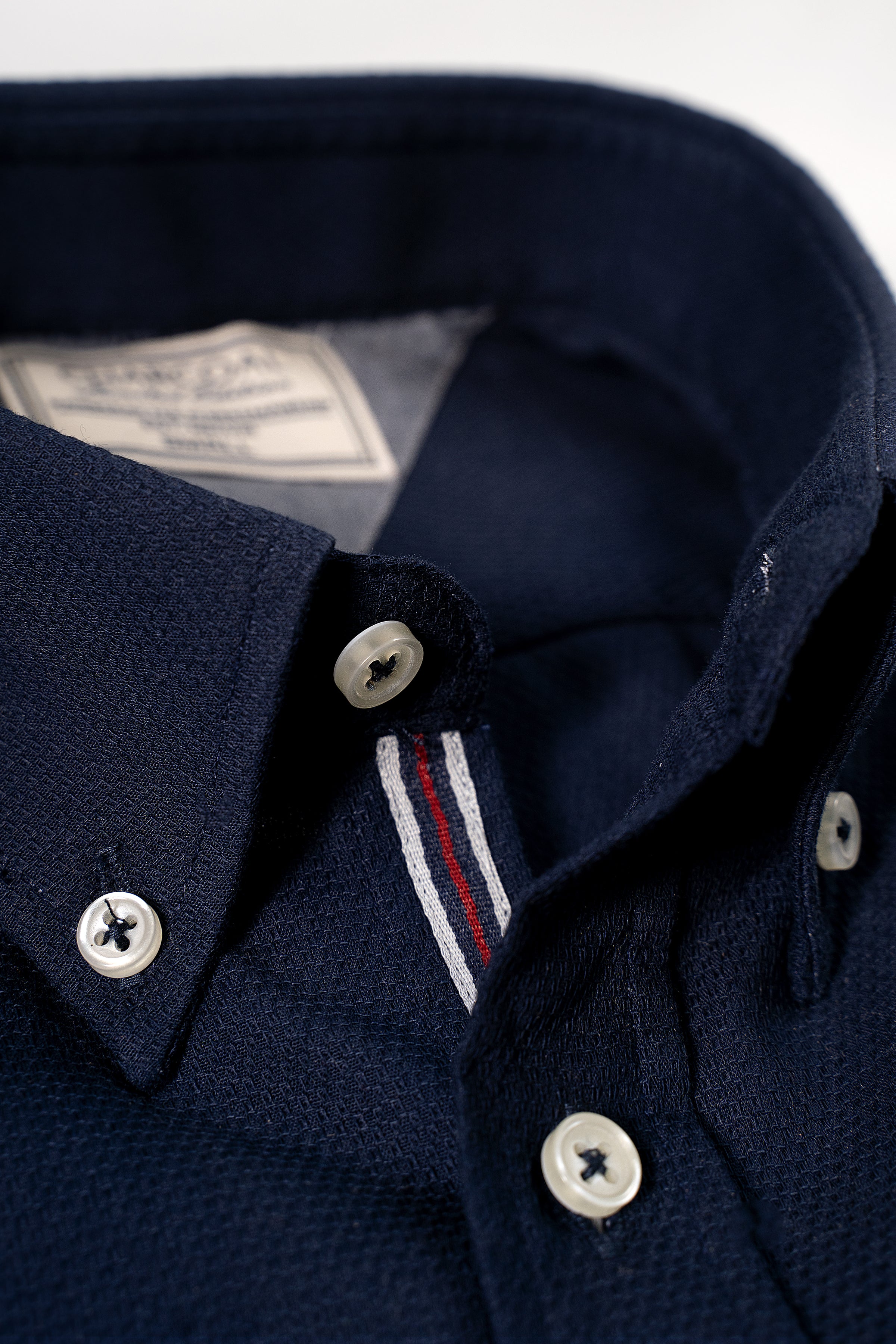 Navy textured dress shirt close-up of button placket, collar, and striped trim