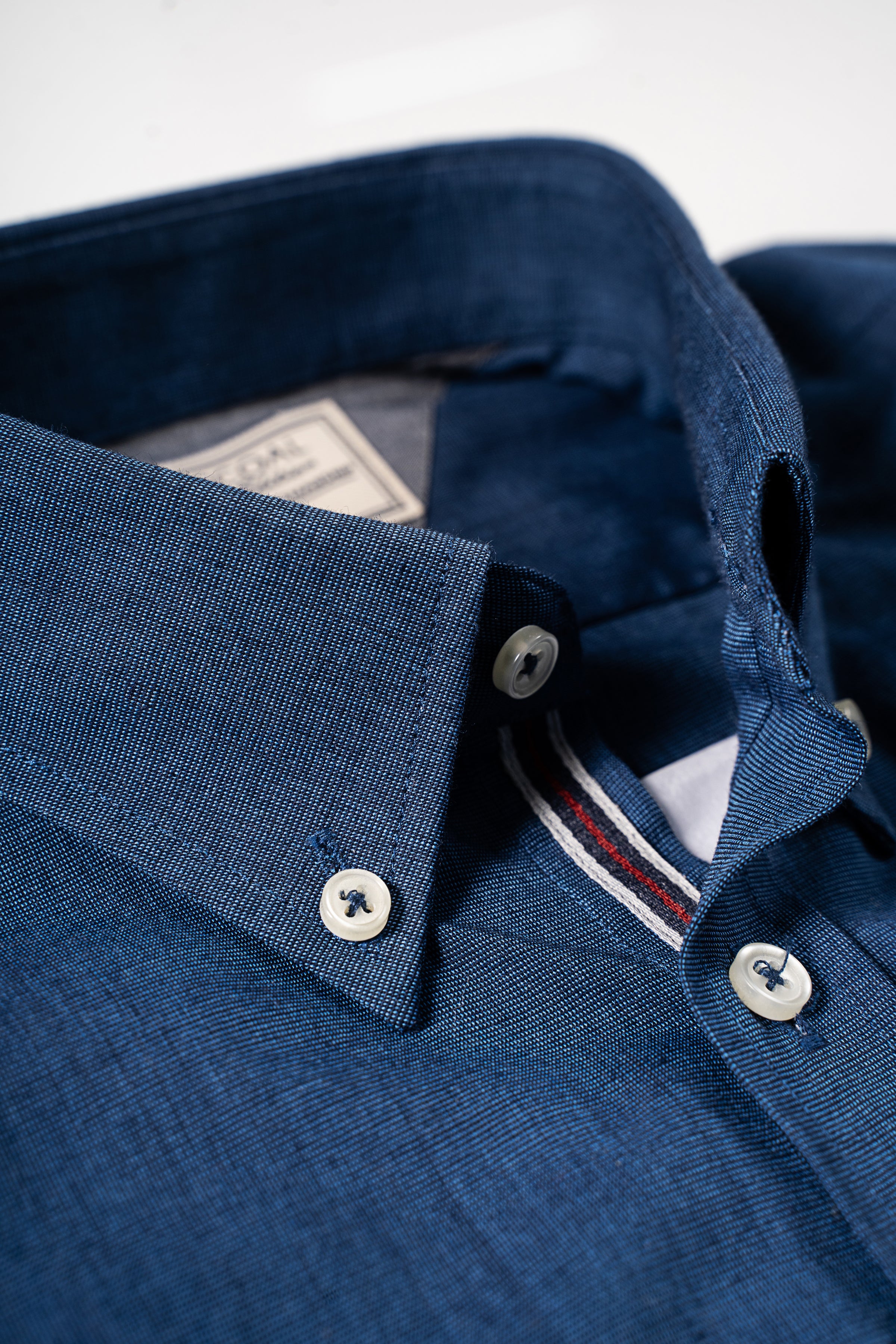 Blue textured shirt collar and button placket, close-up with inner label