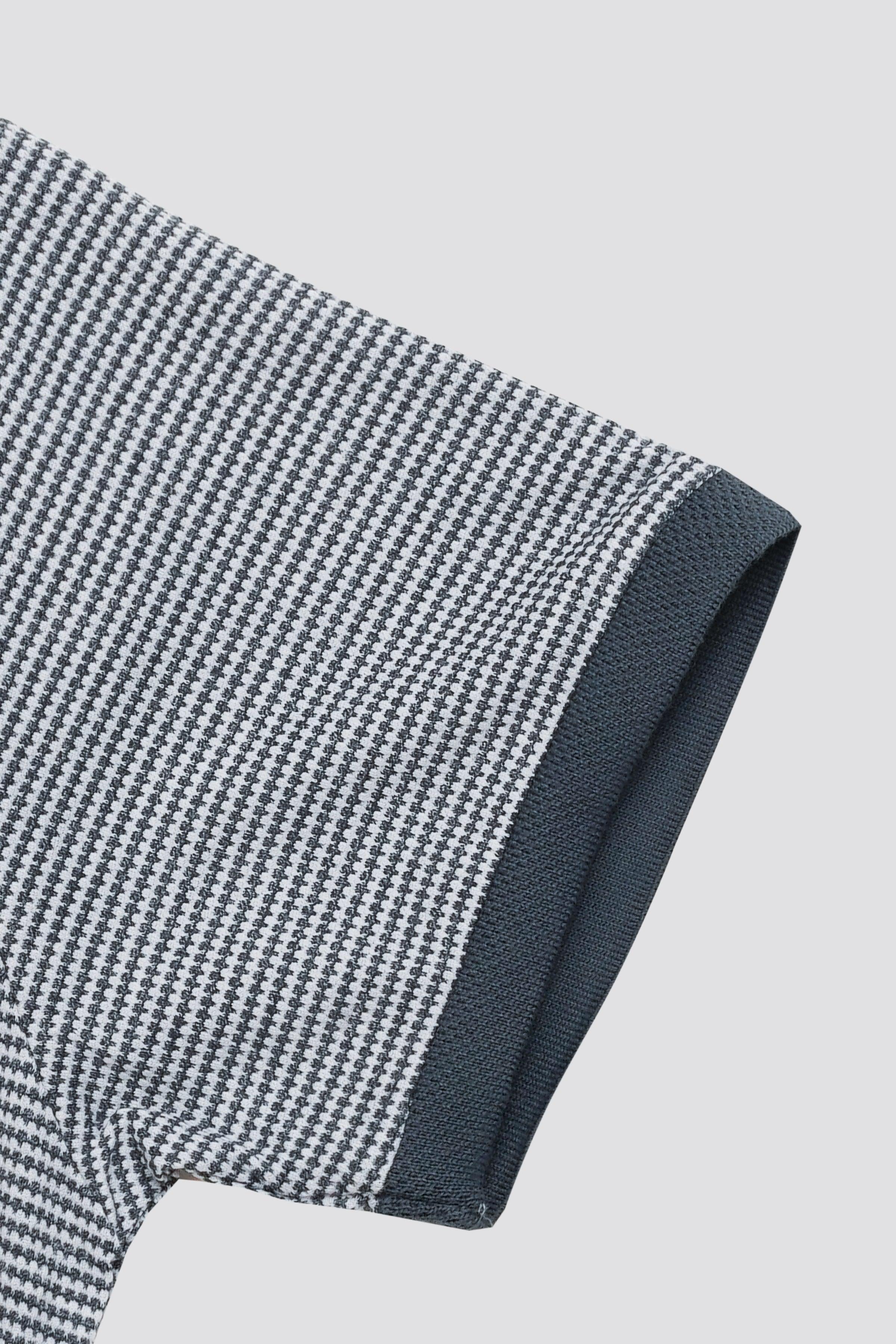 Houndstooth polo sleeve with navy cuff and contrast trim along the edge