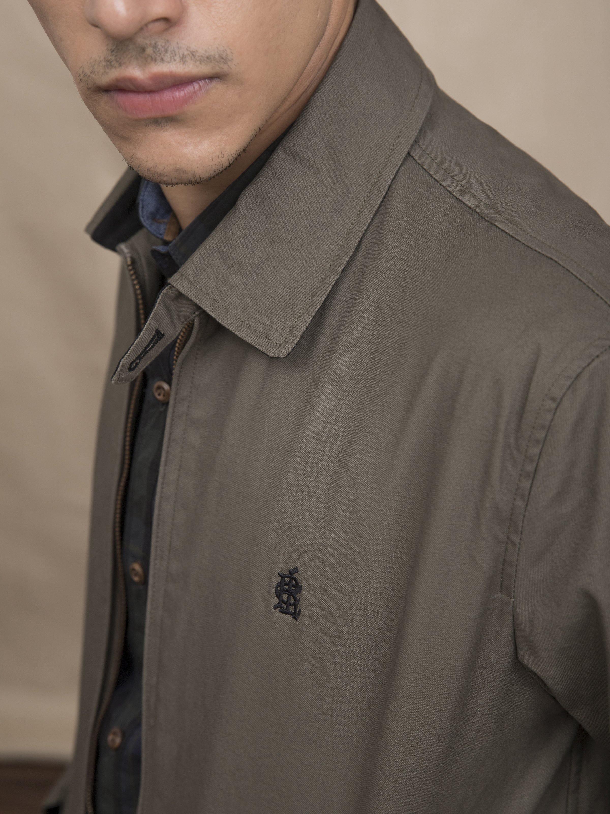 Olive jacket close-up: collared neckline and small chest logo on zip placket