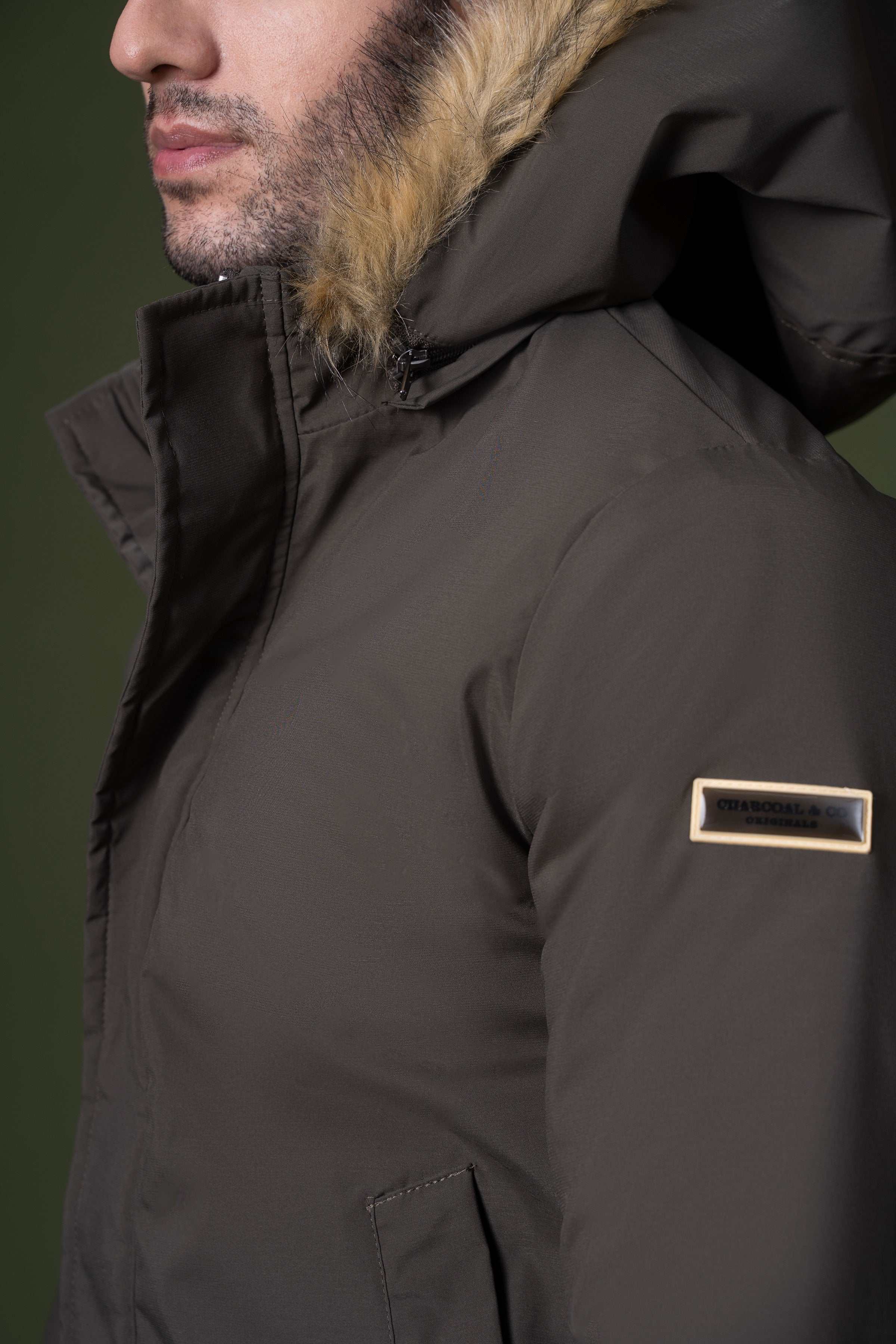 Olive fur-trim hood jacket close-up with logo label on chest