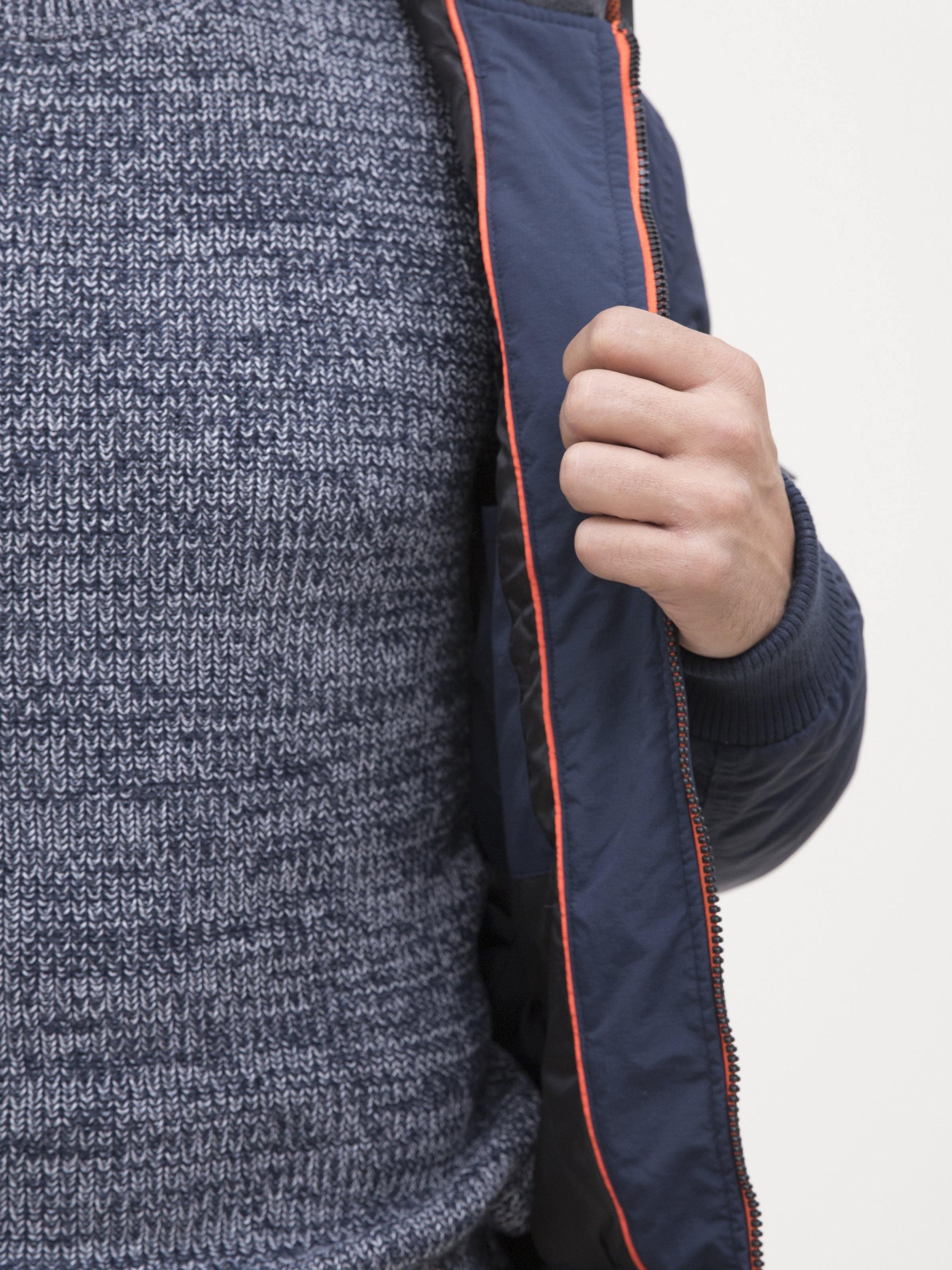 Navy jacket sleeve close-up with orange piping zipper and knit inner lining