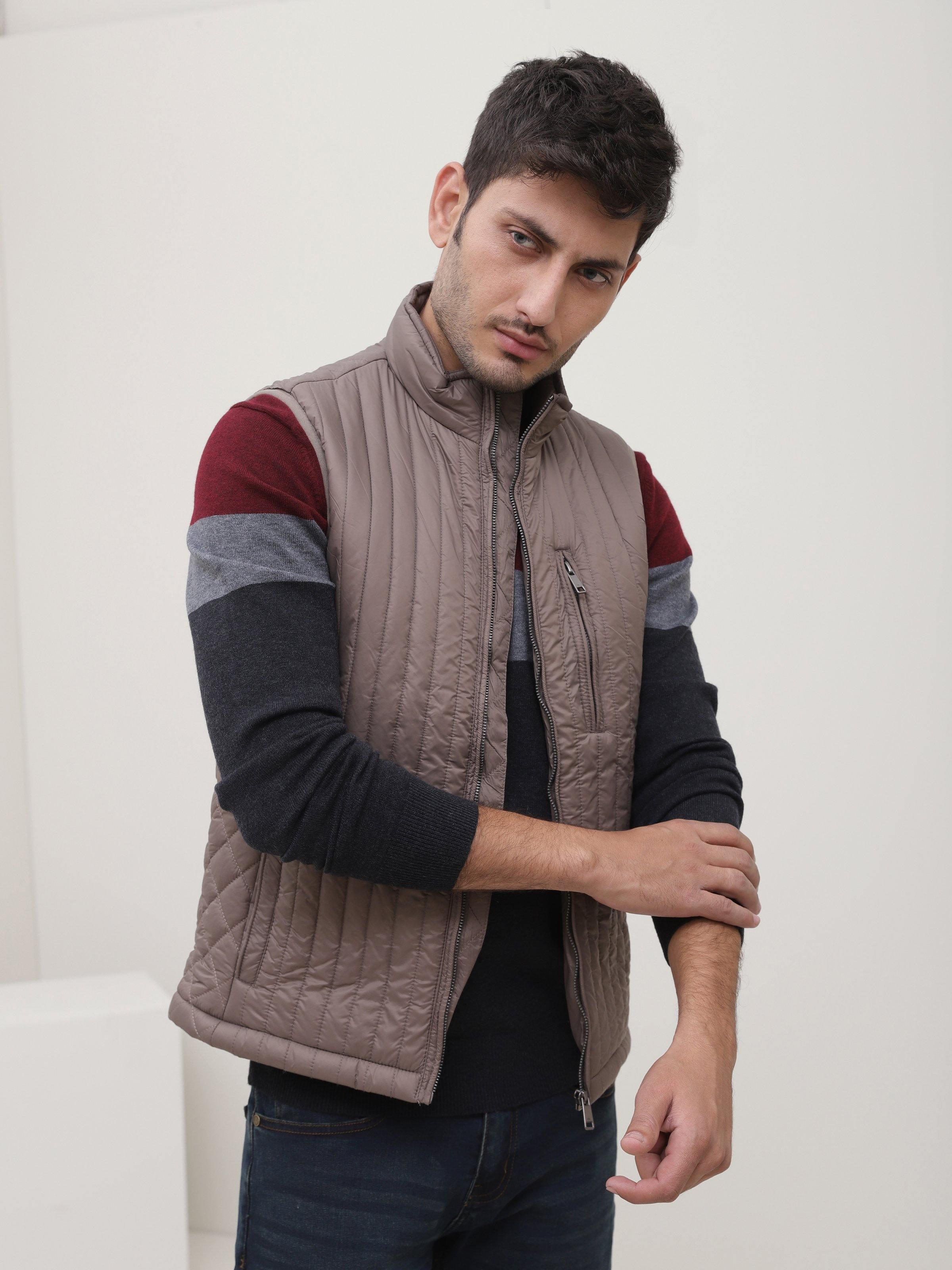 Taupe quilted sleeveless jacket with stand collar and front zipper, worn over sleeves