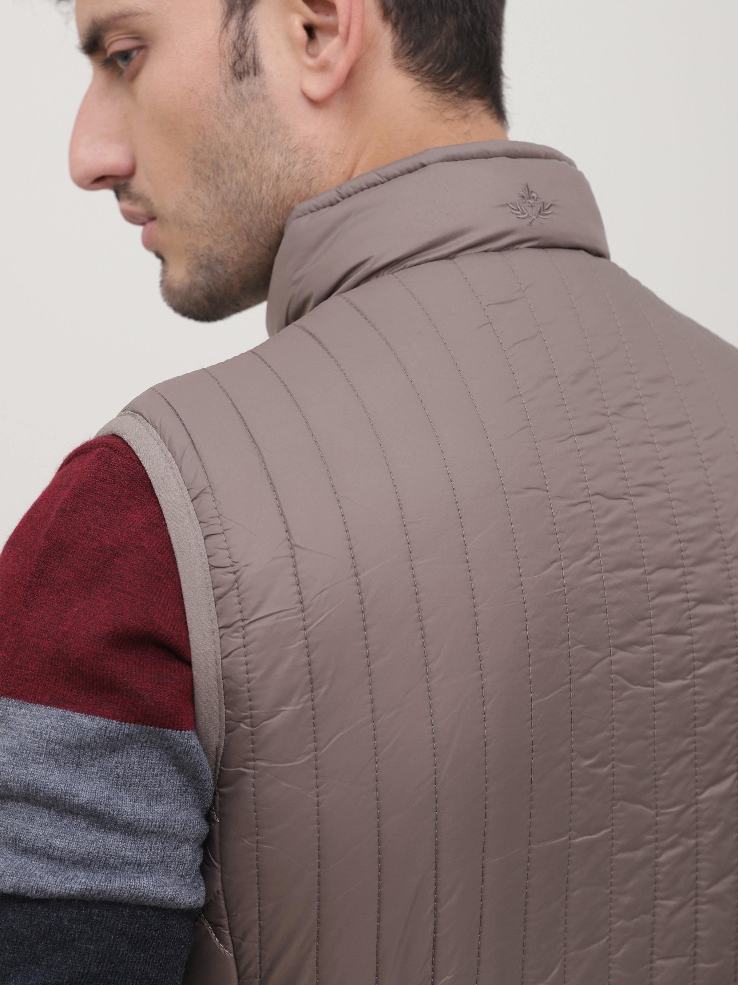 Close-up of taupe quilted sleeveless jacket collar and shoulder seam
