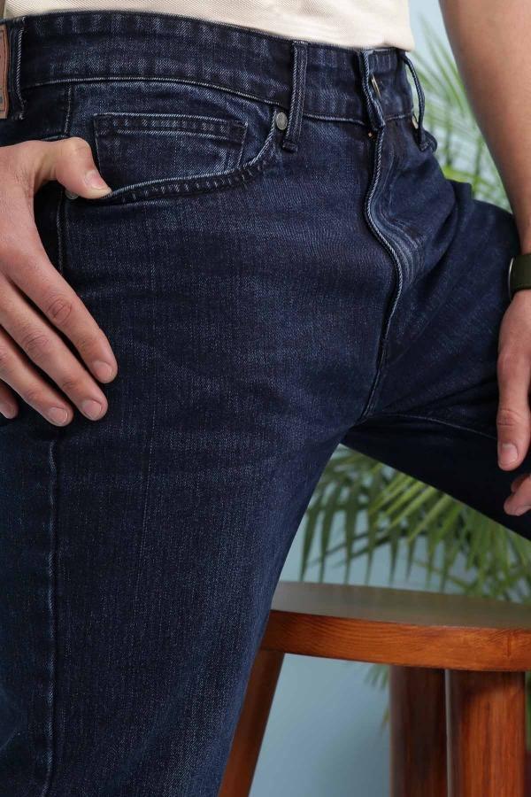 Dark blue denim jeans close-up of waistband, button, and front pockets