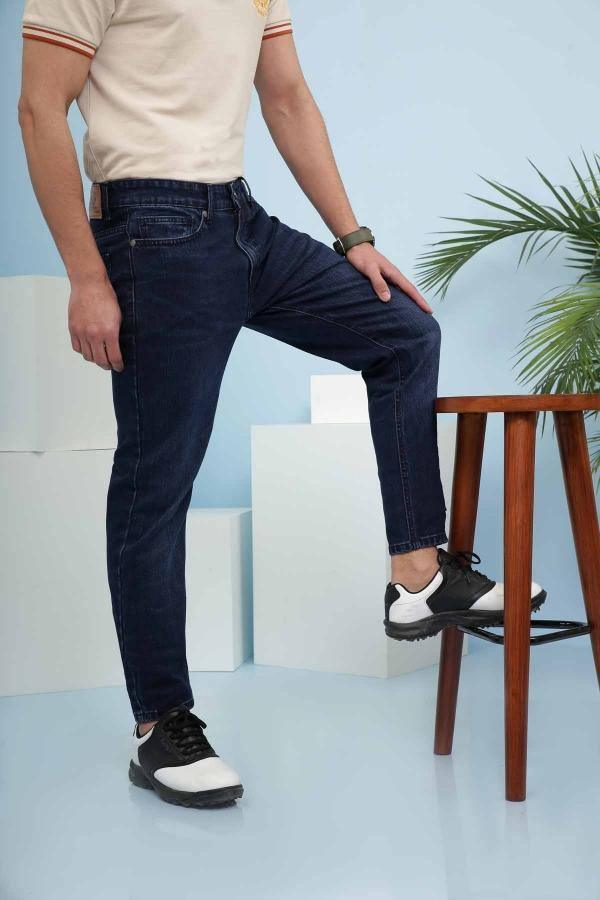 Dark blue slim-fit jeans with tapered leg and rolled cuff in standing pose