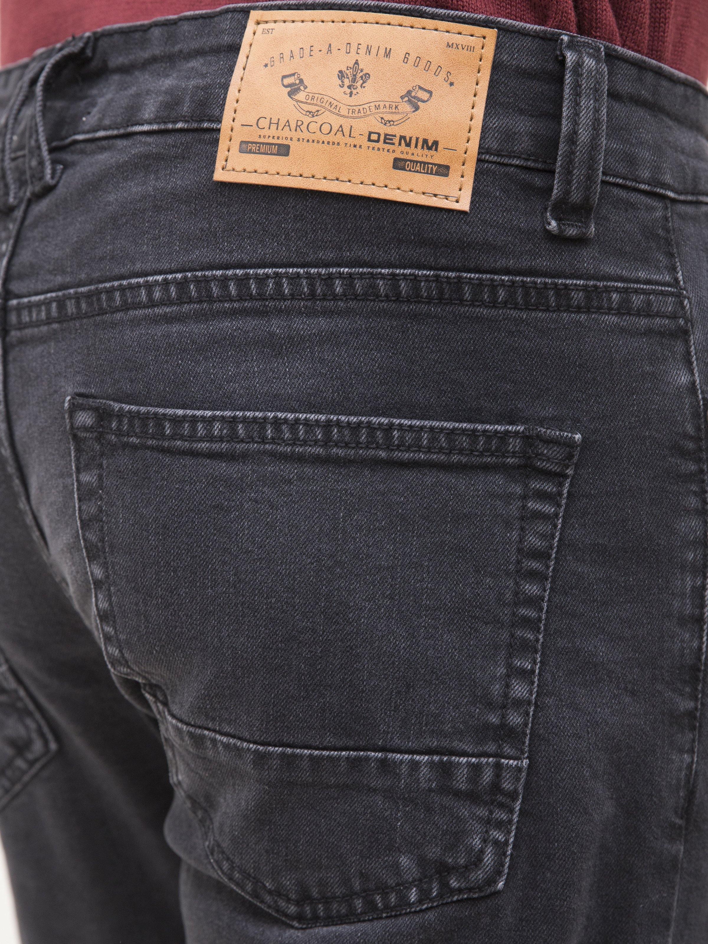 Dark grey jeans close-up of brand patch and front pocket stitching.