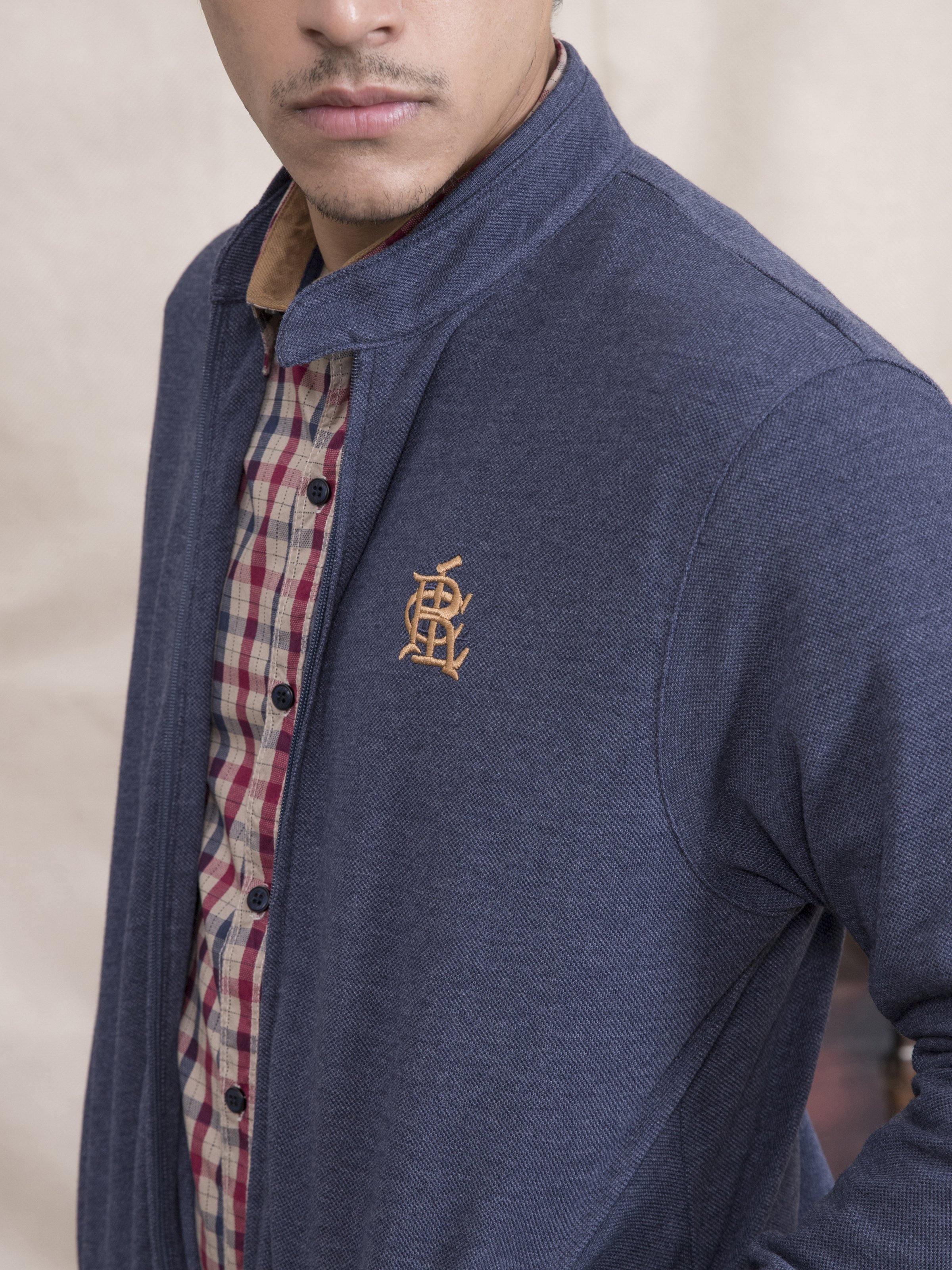 Navy blue knit jacket with stand collar, partial plaid shirt, and chest logo