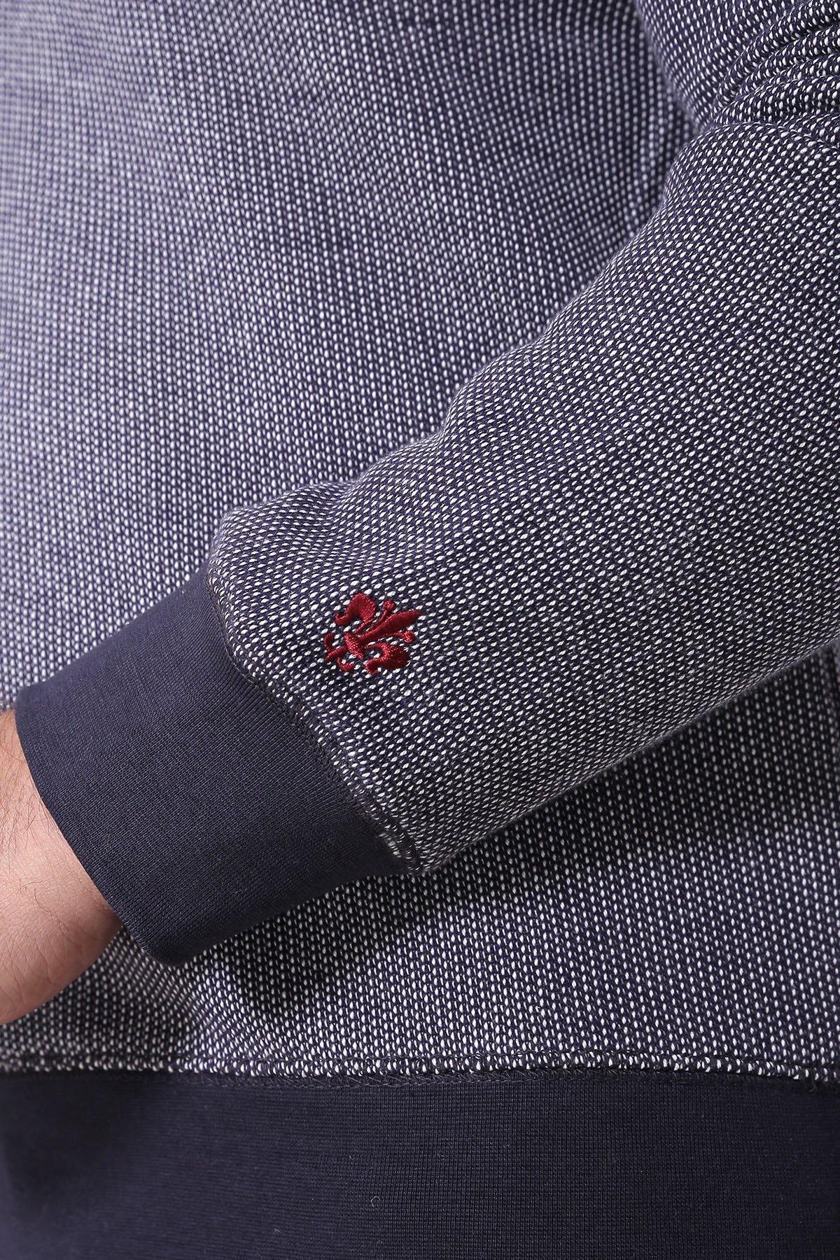 Close-up of charcoal gray sweatshirt sleeve with navy cuff and red cross-stitch logo