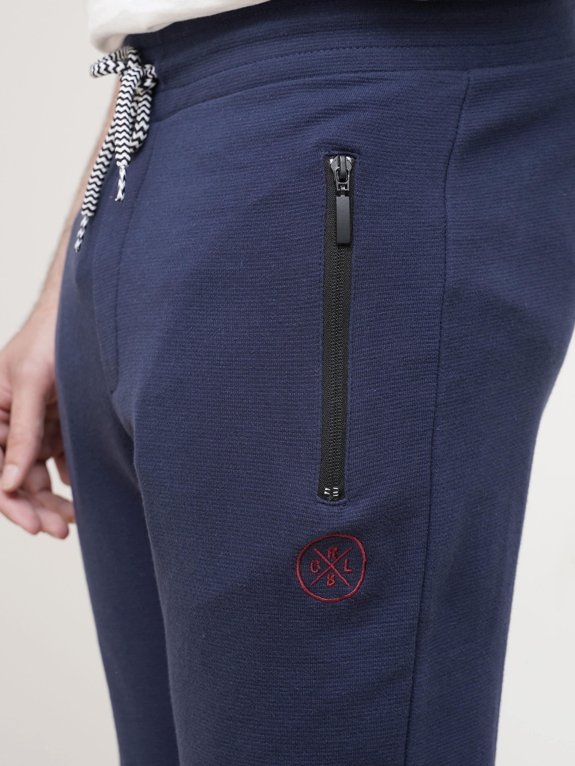 Dark blue jogger trousers with side zip pocket and logo patch at hip