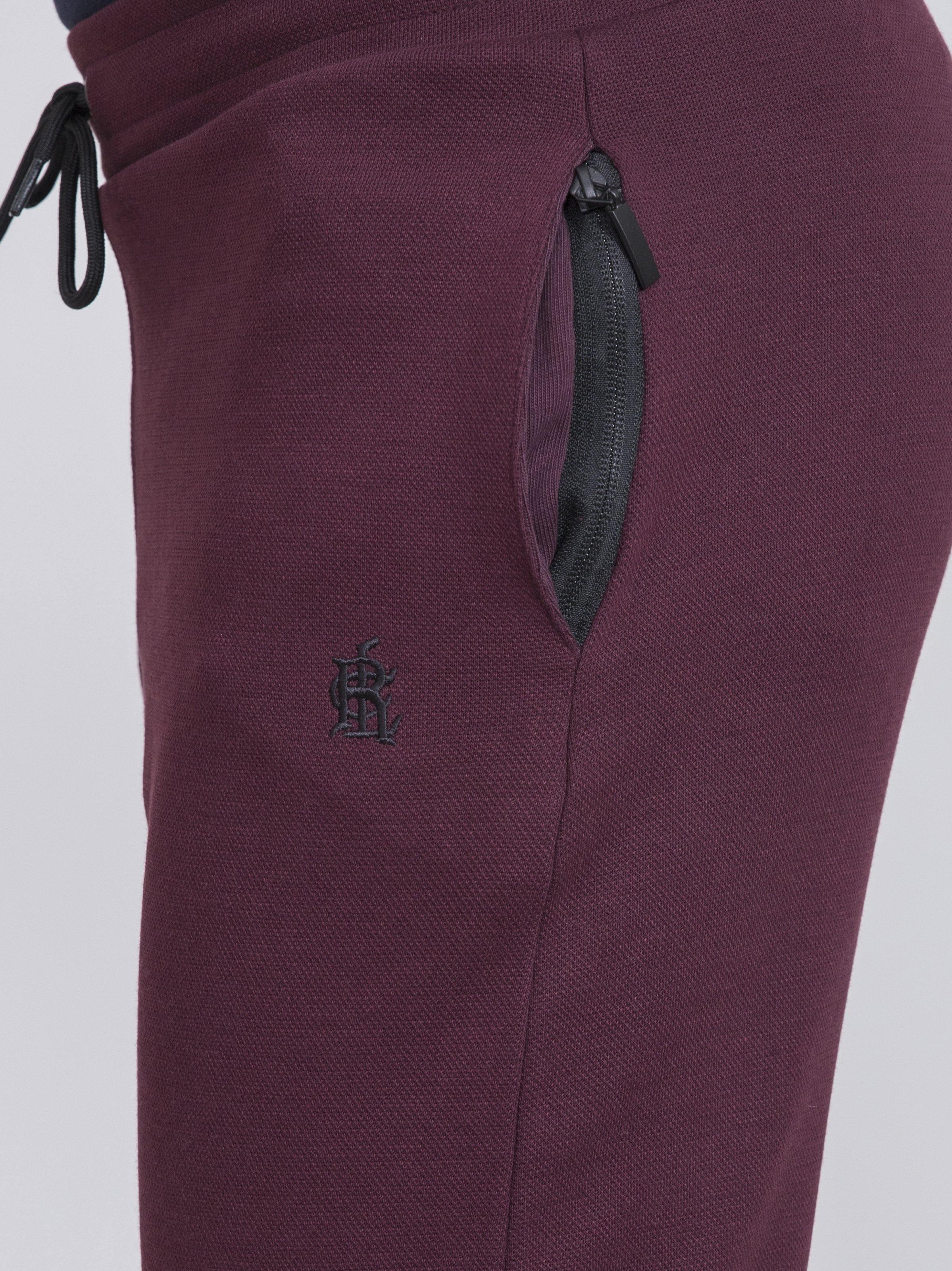 Maroon slim-fit trousers with side zip pocket and embroidered logo at thigh
