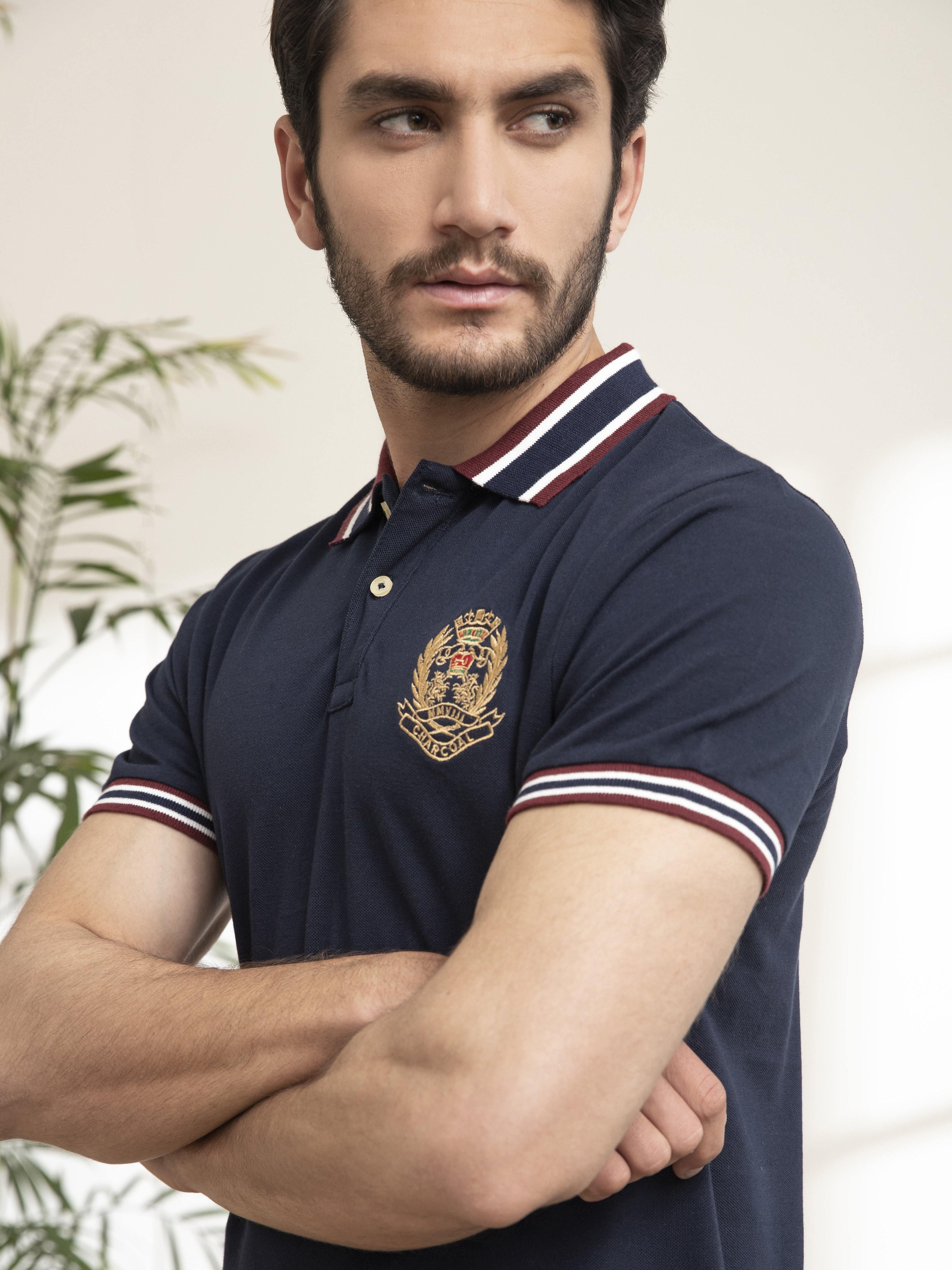 Navy polo shirt collar with red-white-blue stripes and crest patch on chest