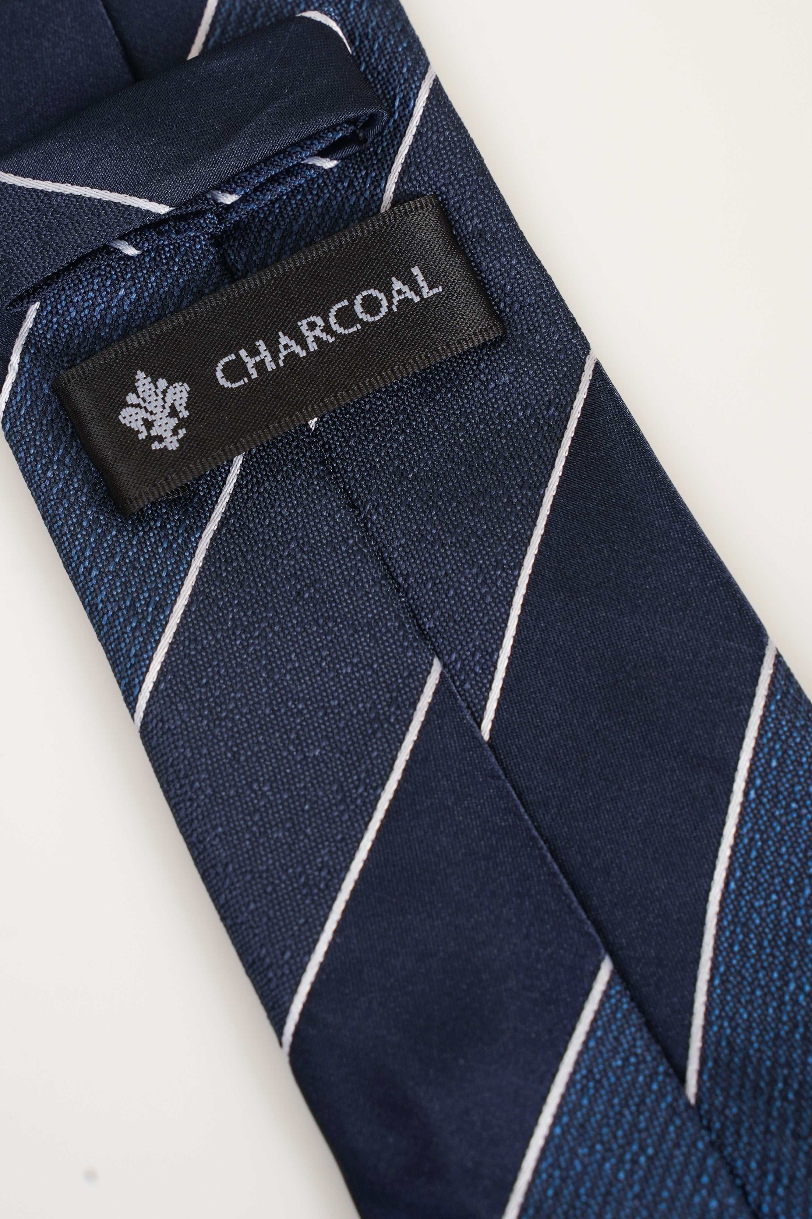 Striped tie with navy weave, white diagonal stripes, and CHARCOAL brand tag
