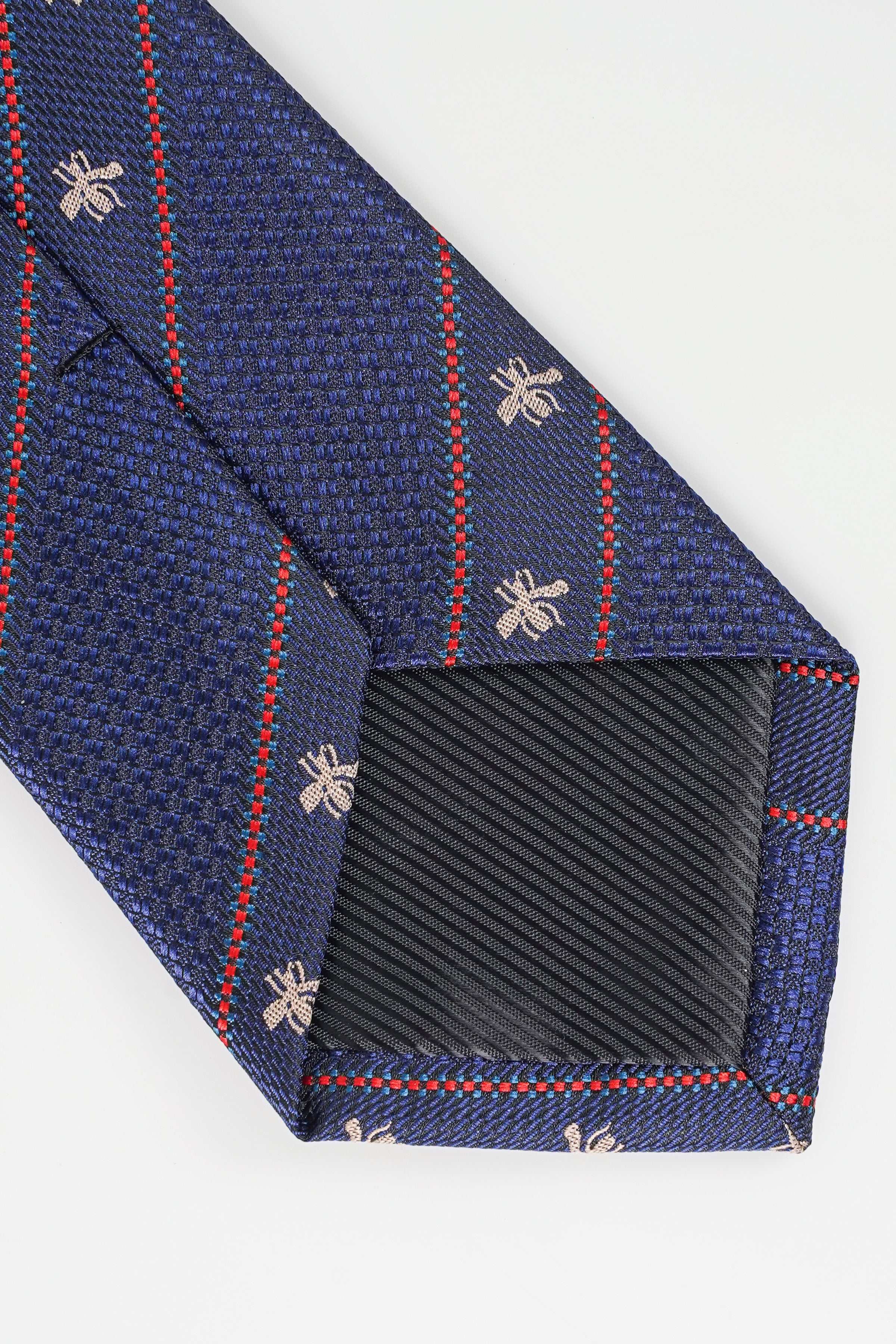 Blue poly silk tie with woven texture, red plaid trim, and fleur-de-lis pattern