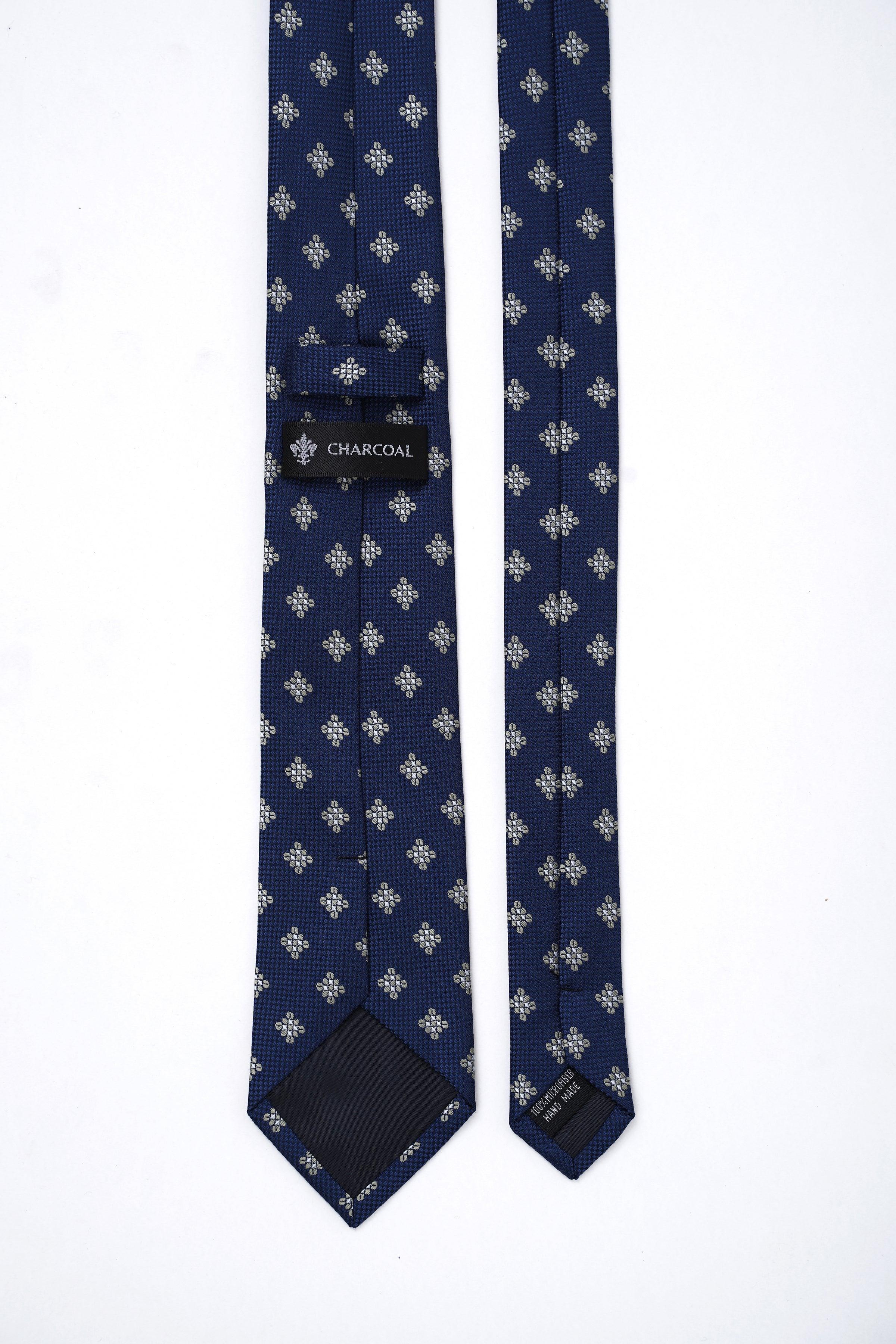 Blue poly silk tie with repeating floral pattern and 'CHARCOAL' brand label at tip