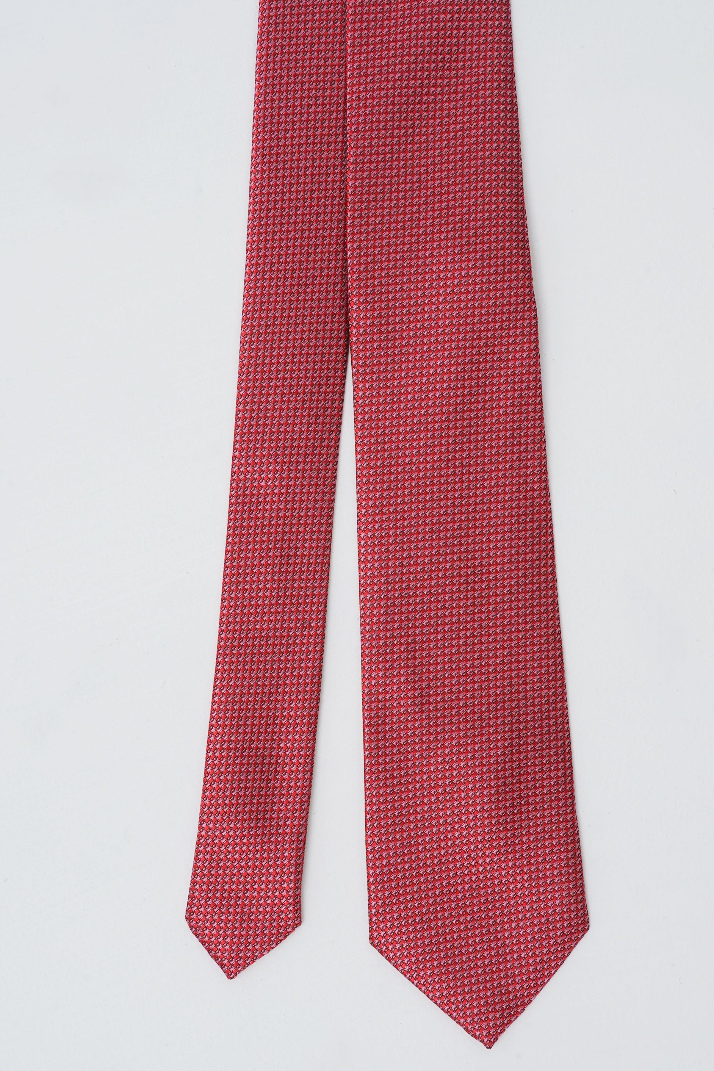 Red patterned poly silk tie hanging straight with pointed tip.