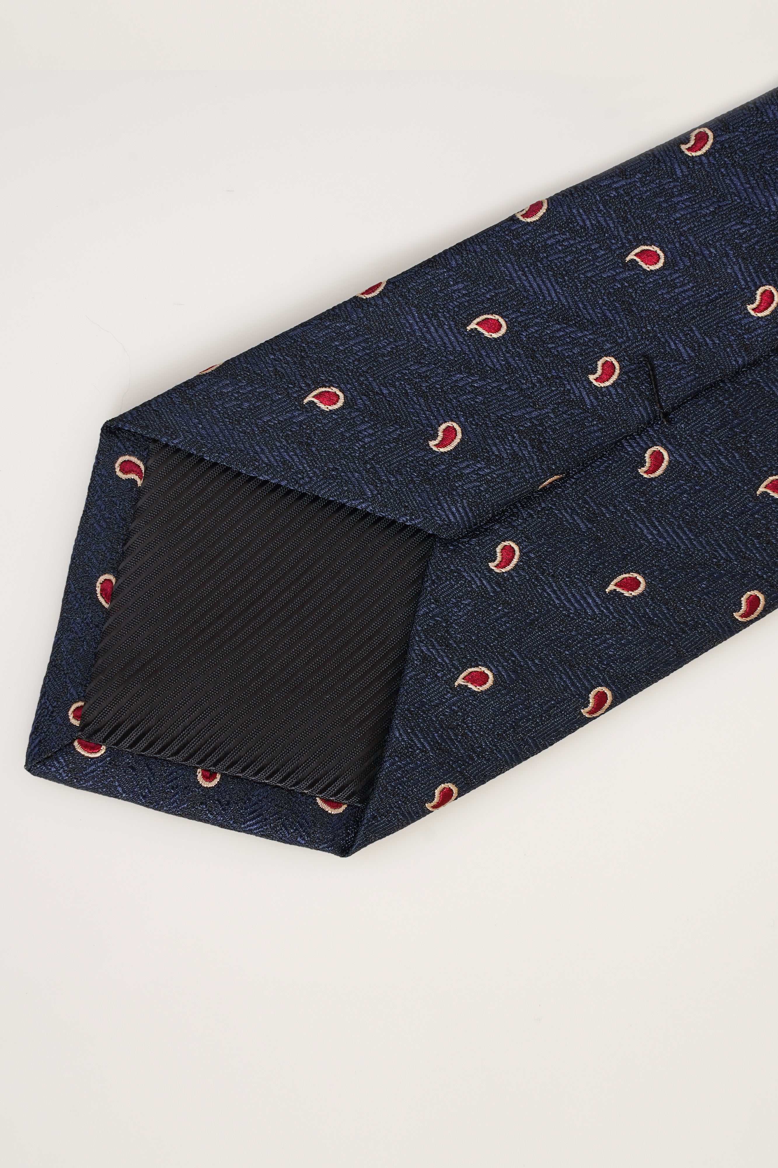 Navy poly silk necktie with red pattern, close-up on pointed end