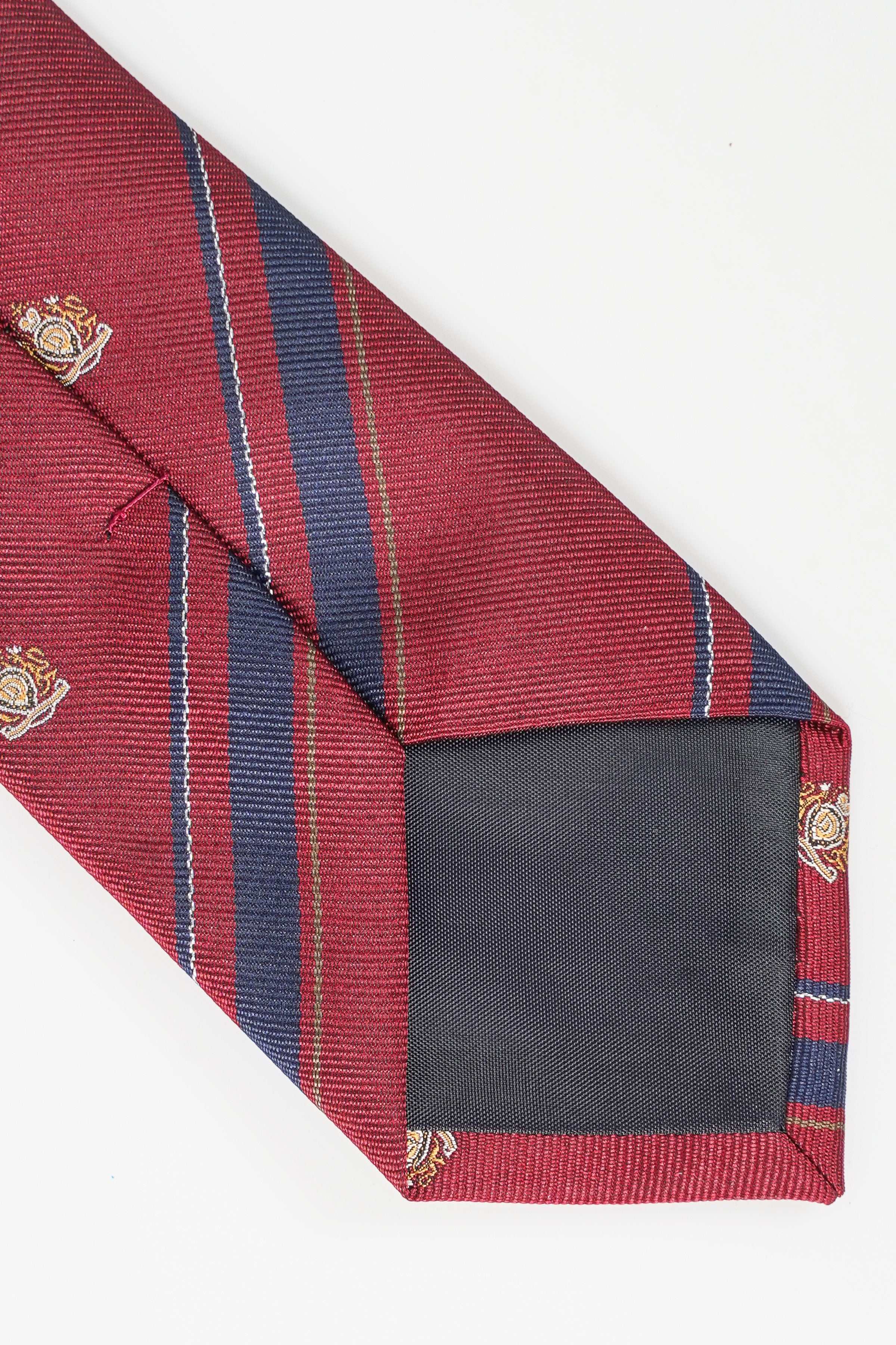 Red necktie with navy stripe trim, gold crest motifs, folded end