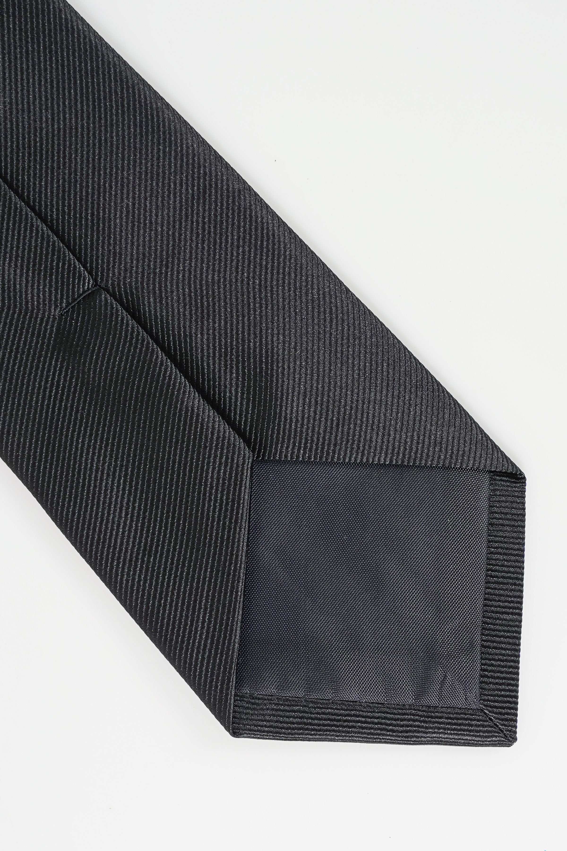 Dark poly silk tie tip and seam detail, textured diagonal weave