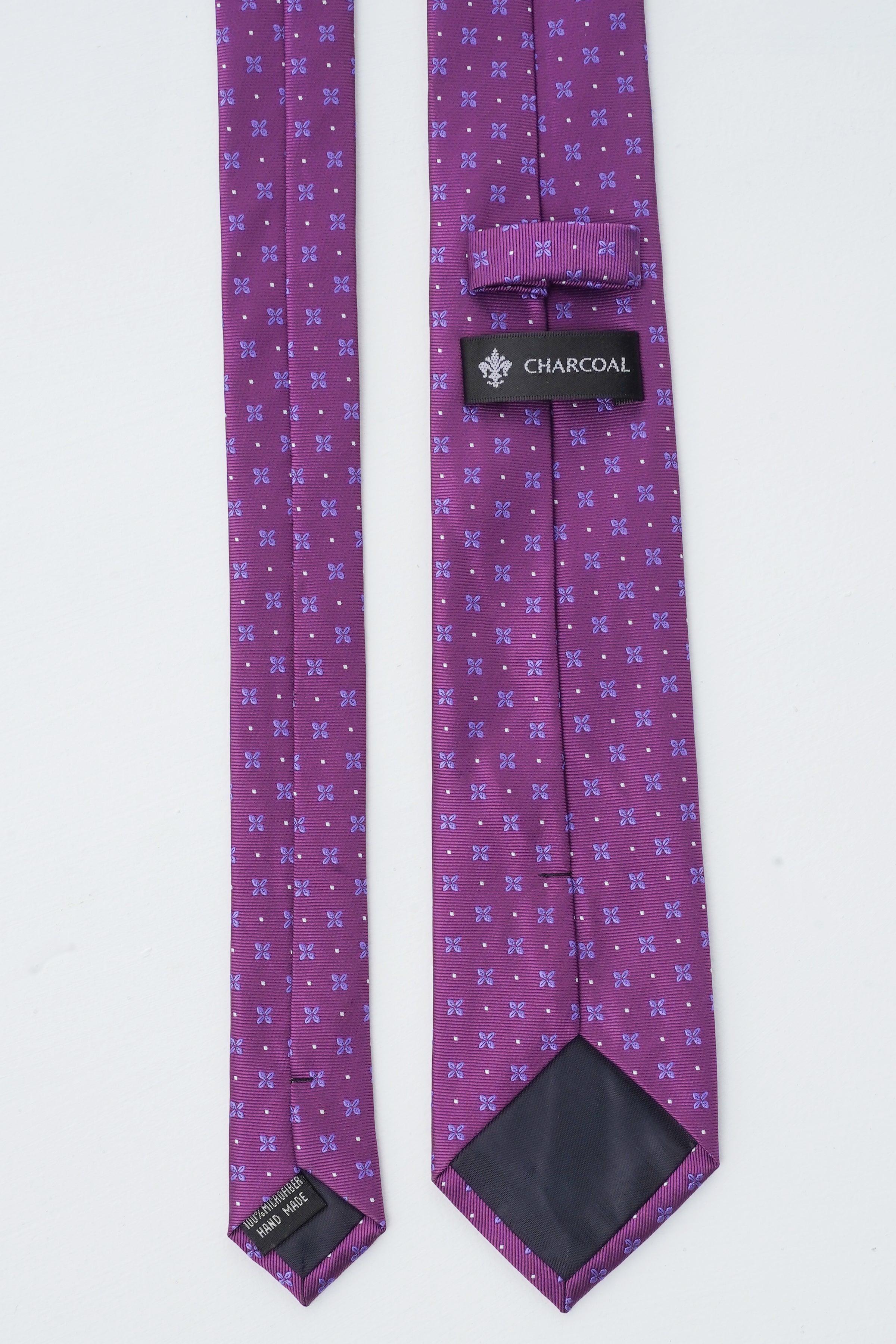 Purple poly silk tie with repeating small pattern and charcoal label at end.