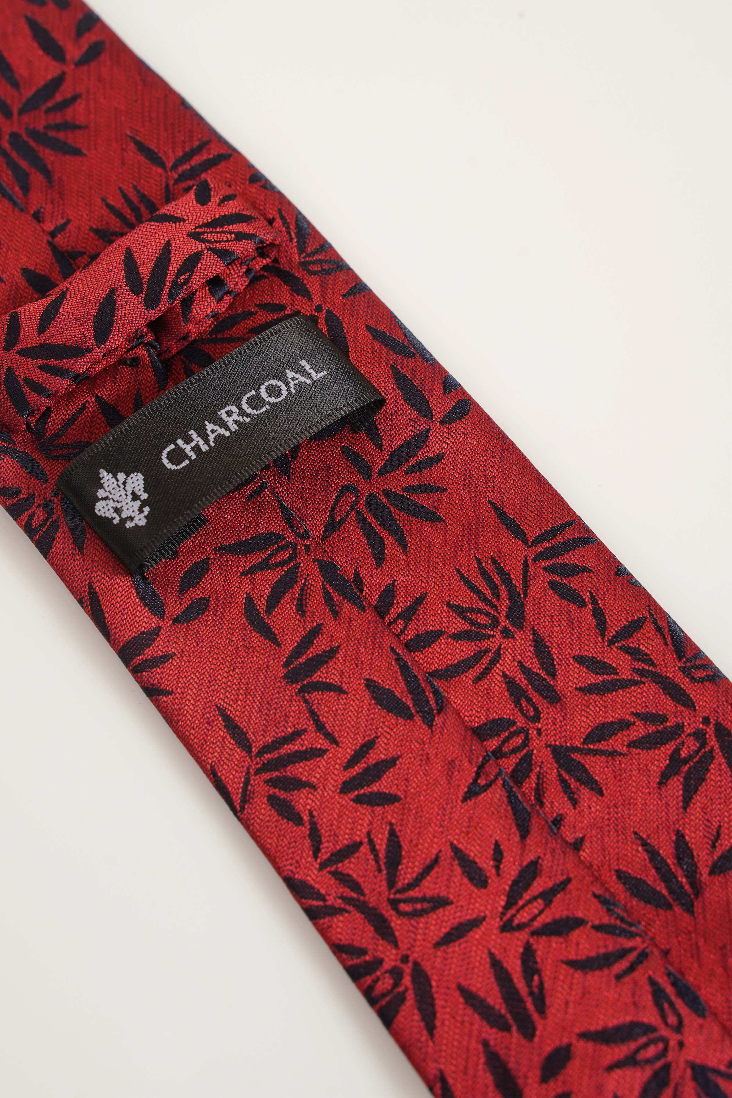 Red patterned tie with 'CHARCOAL' label on the keeper and leaf motif
