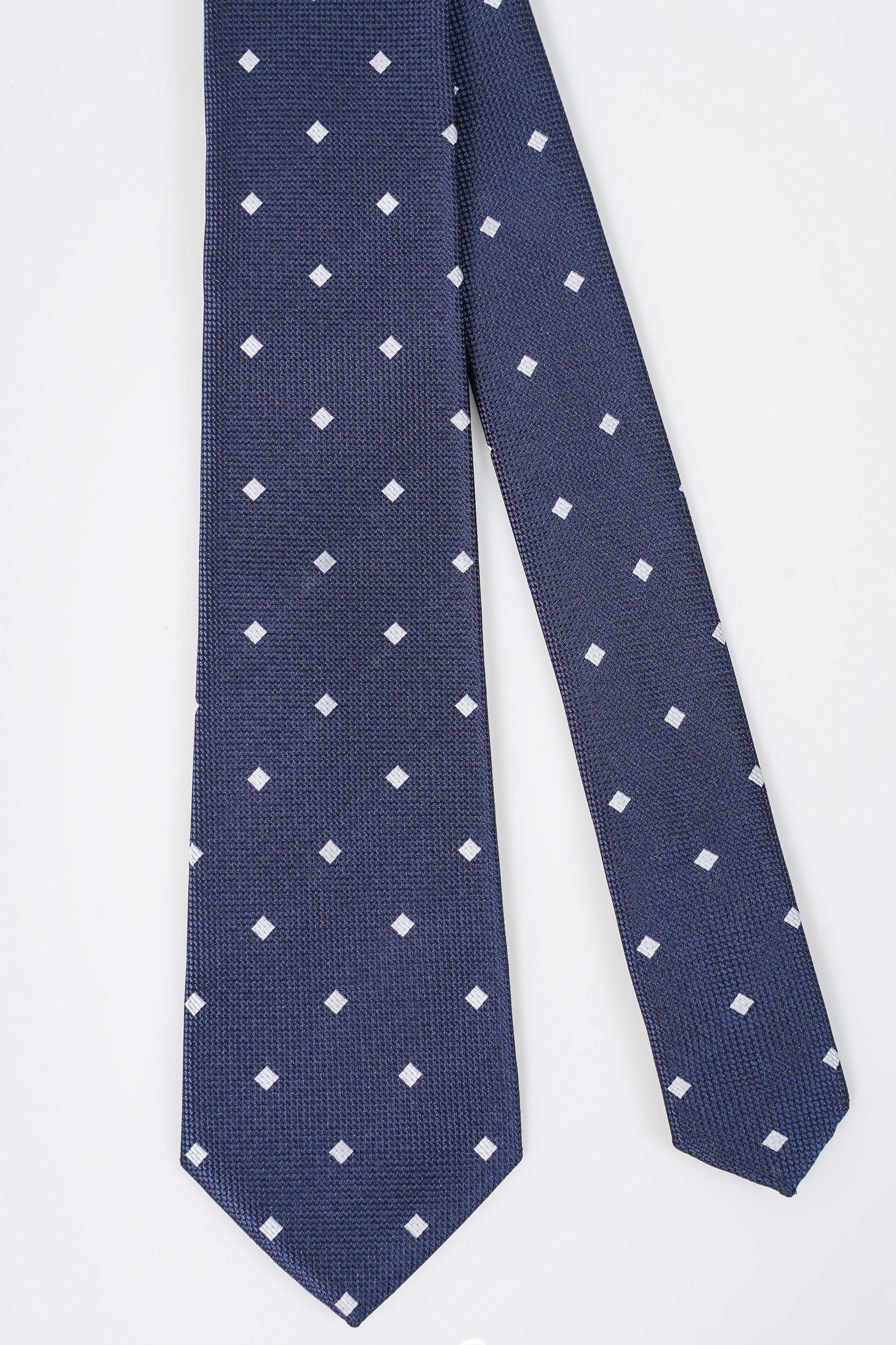 Navy blue tie with repeating white square motifs, close-up view
