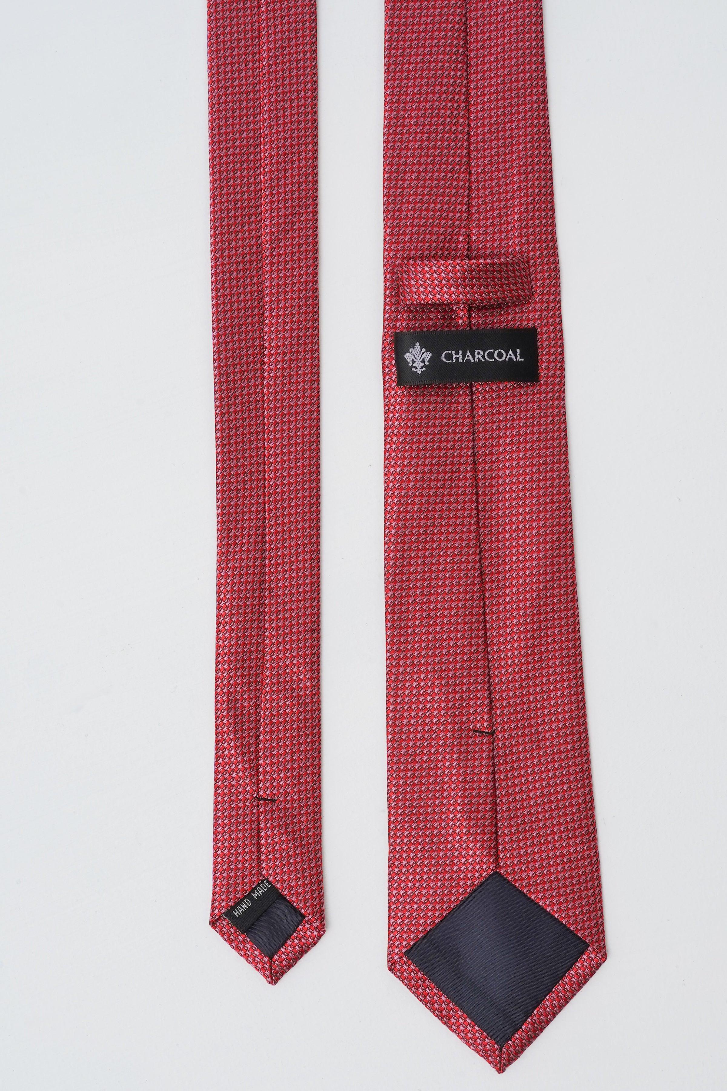 Red poly silk tie close-up with charcoal brand label at keeper.