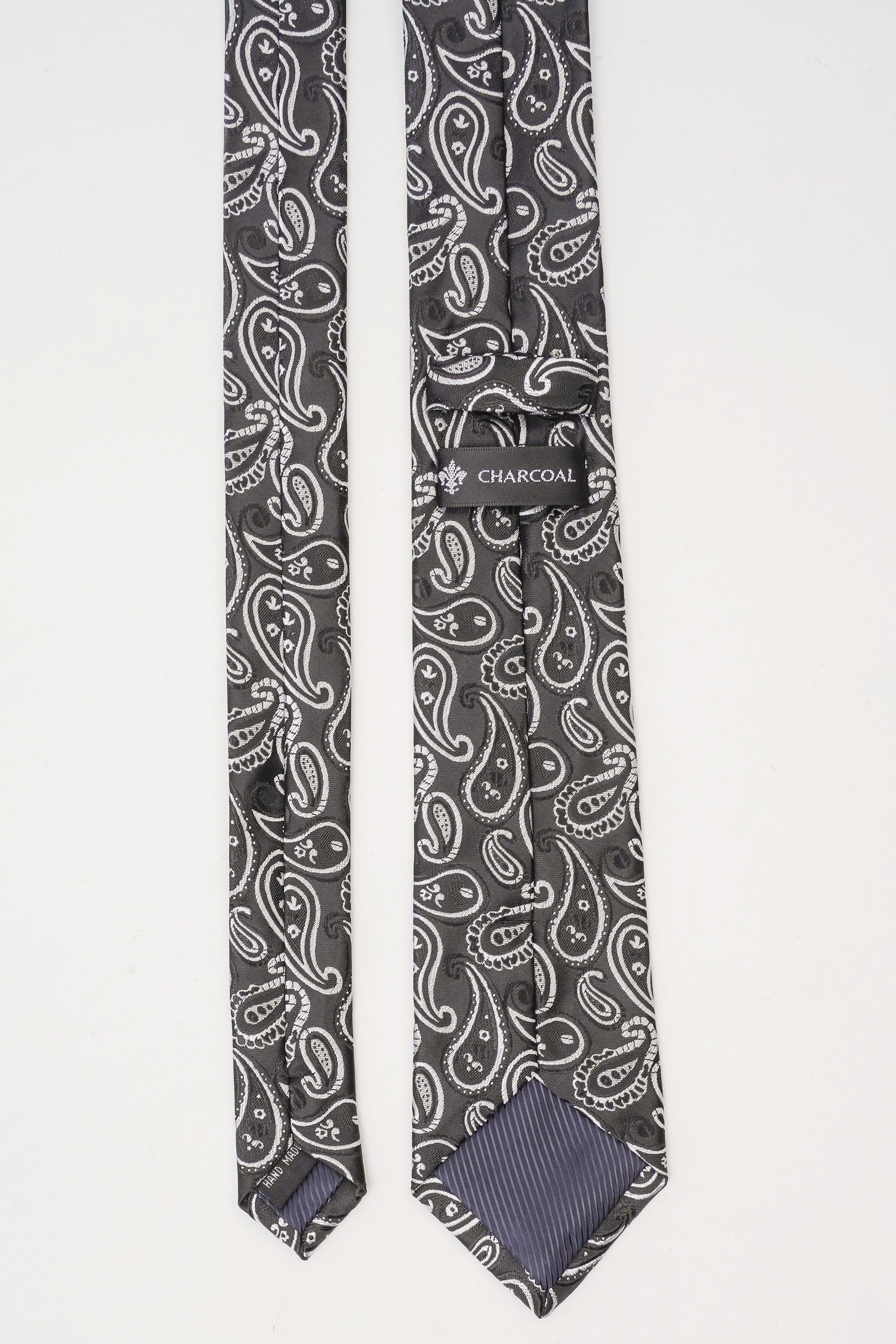 Poly silk tie, dark paisley print with light swirls; charcoal label on band