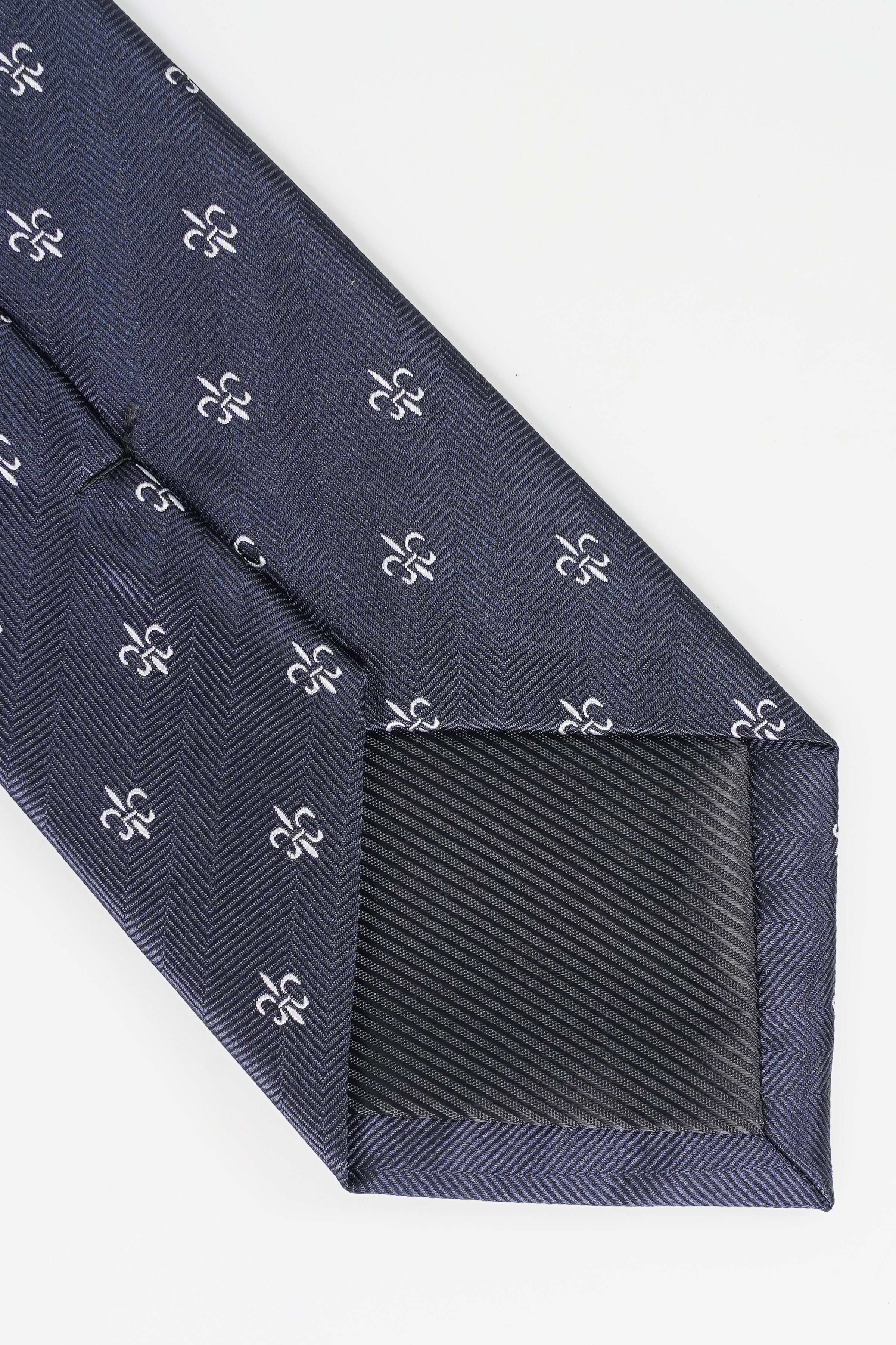 Dark navy tie tip with fleur-de-lis pattern and diagonal weave, close-up