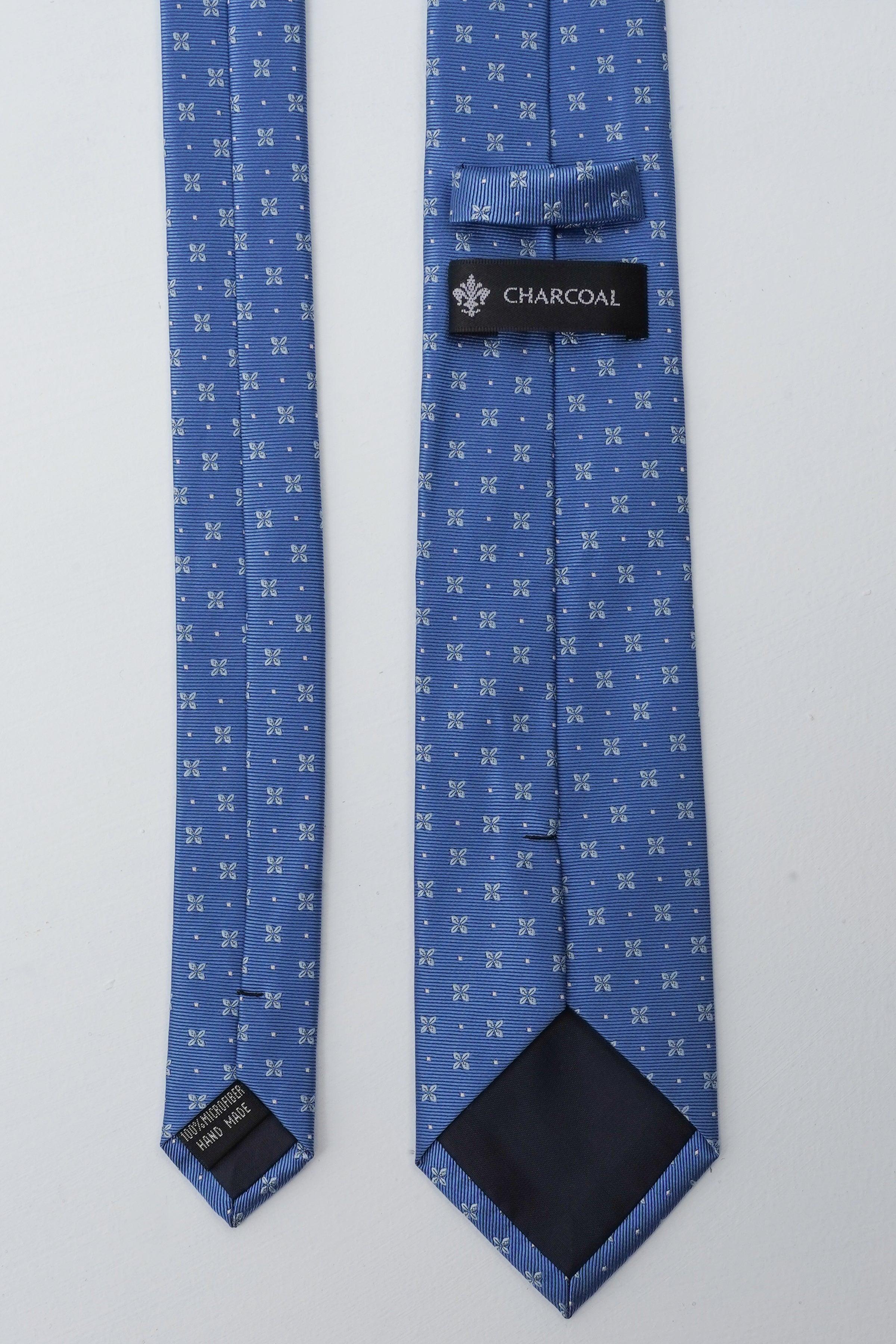 Blue necktie laid flat, small white bow pattern, visible CHARCOAL label near knot