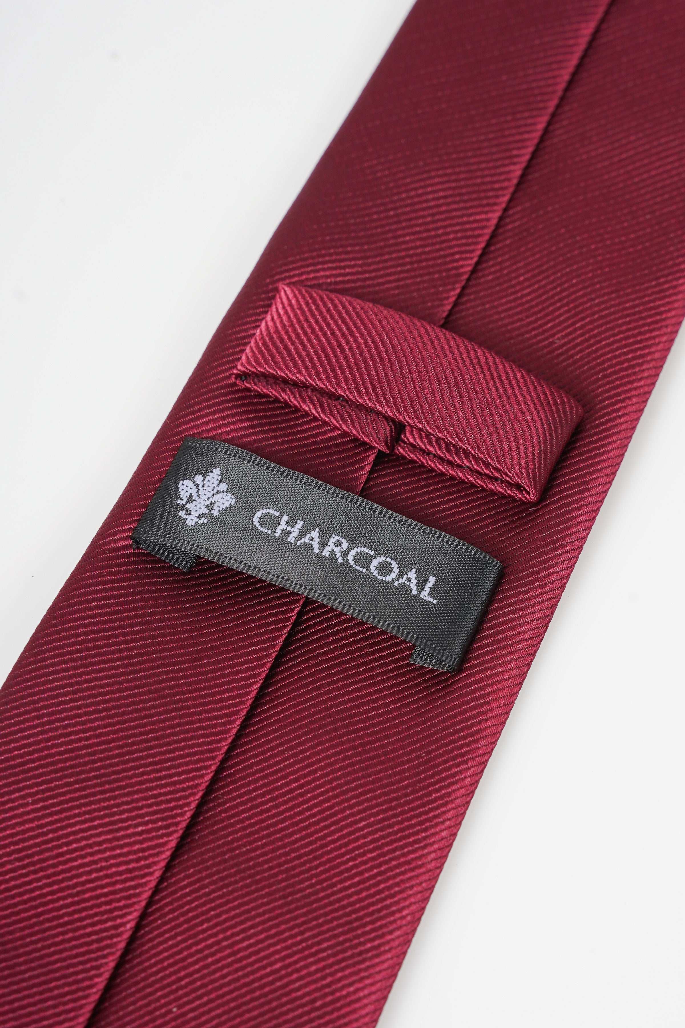 Maroon necktie with CHARCAL label and stitched keeper tab on the blade