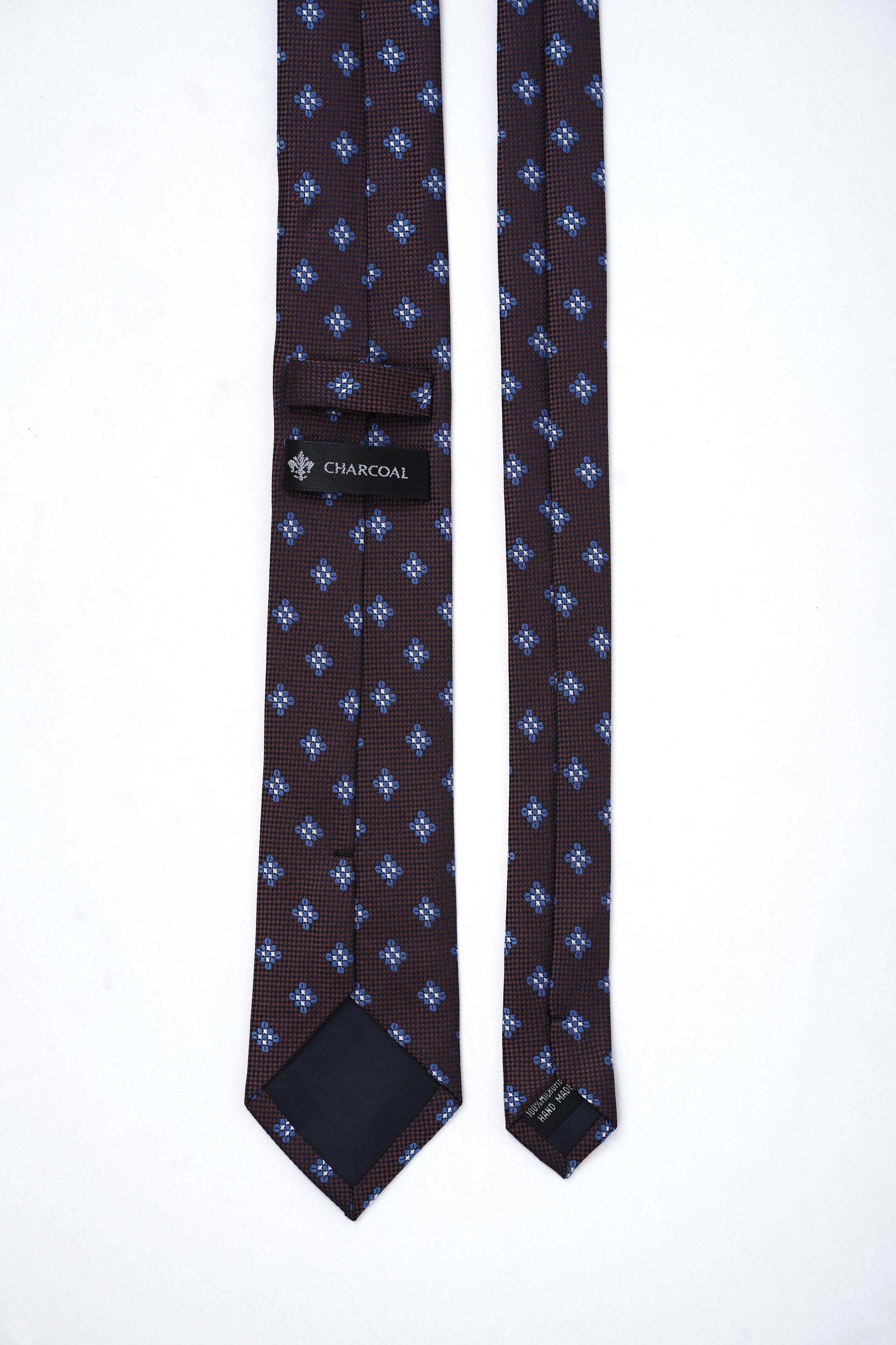 Dark brown necktie with blue quatrefoil pattern and Charcoal label at seam.