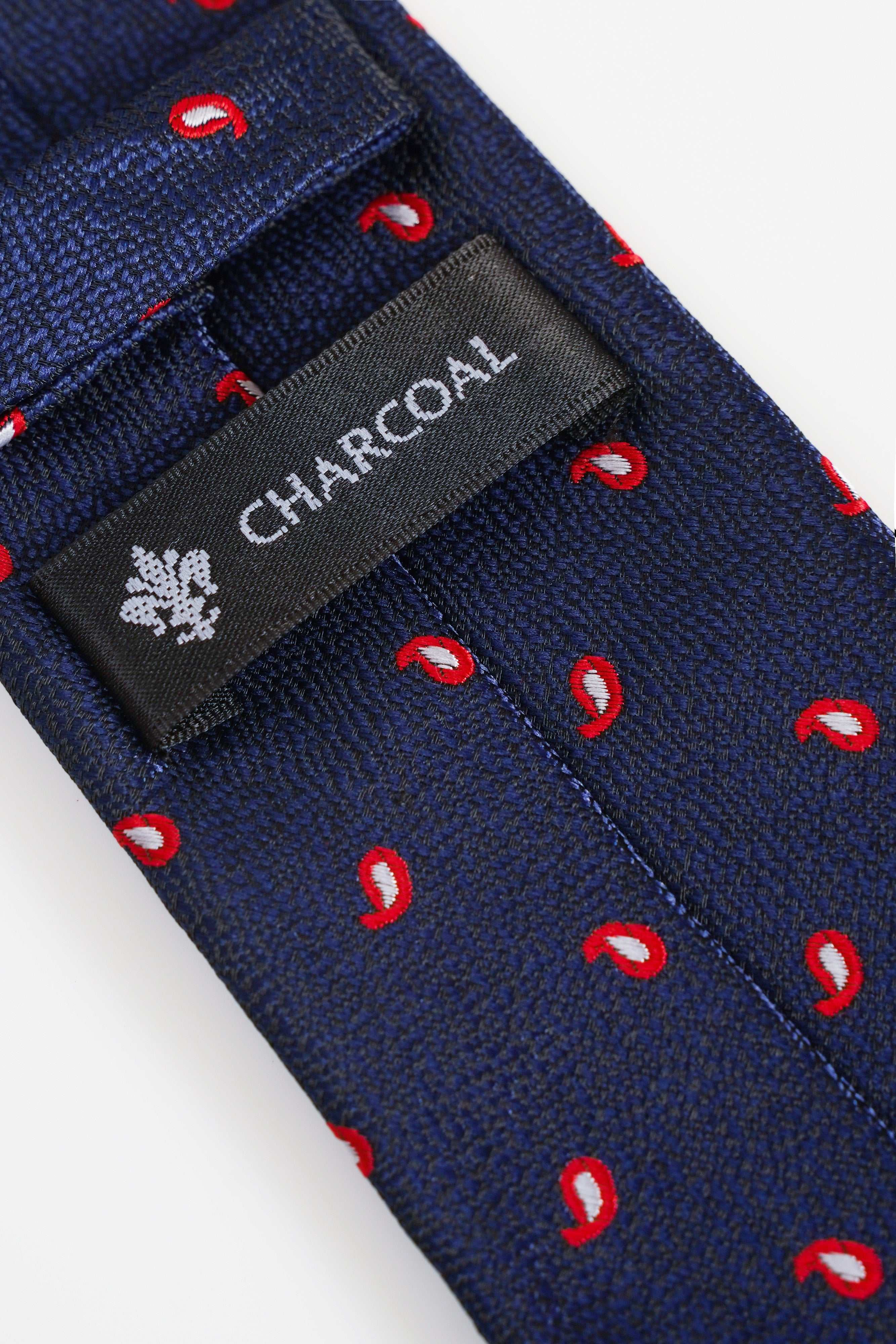 Charcoal brand label on navy poly silk tie with red paisley pattern.