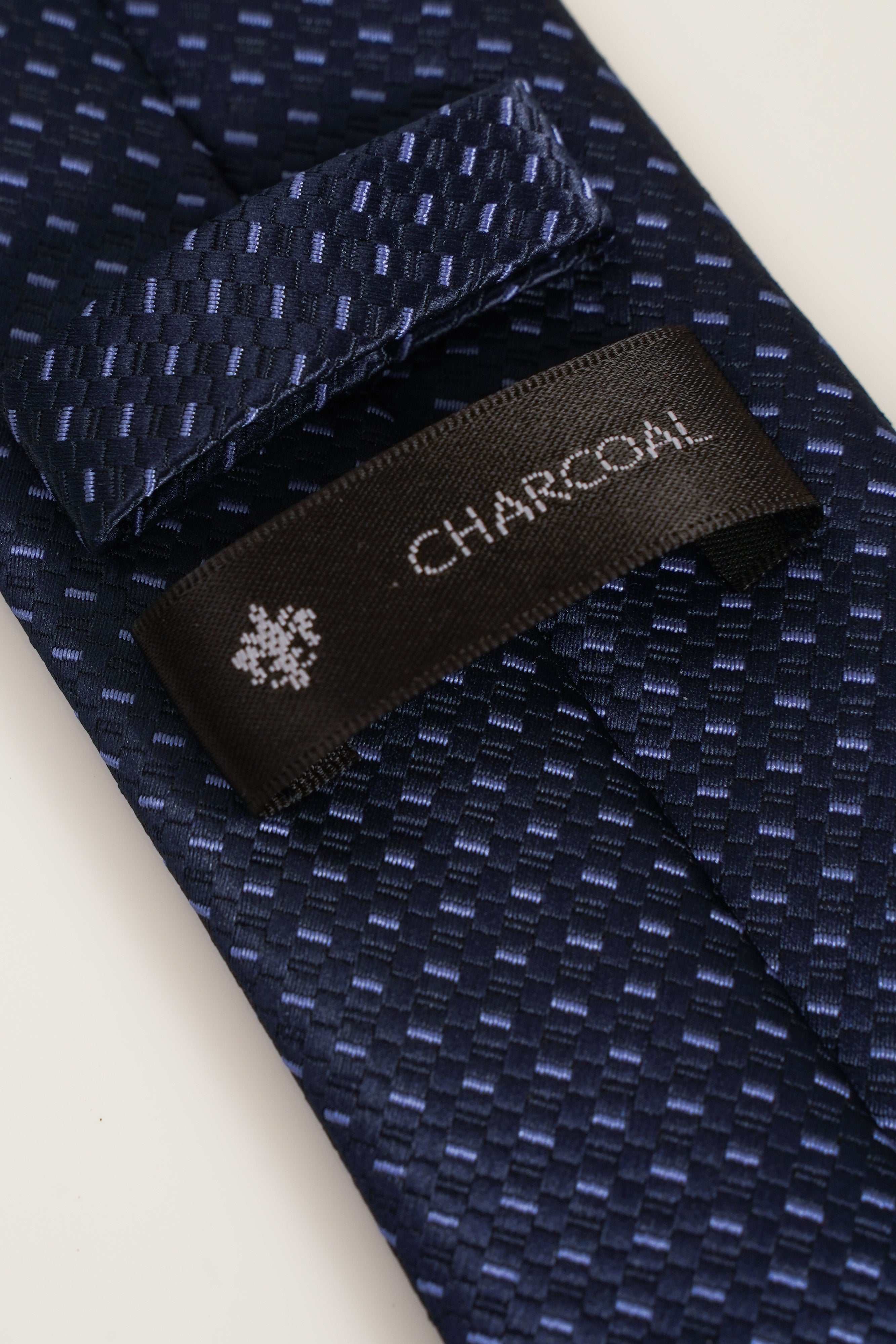Navy patterned tie with fabric label tag and close-up woven texture