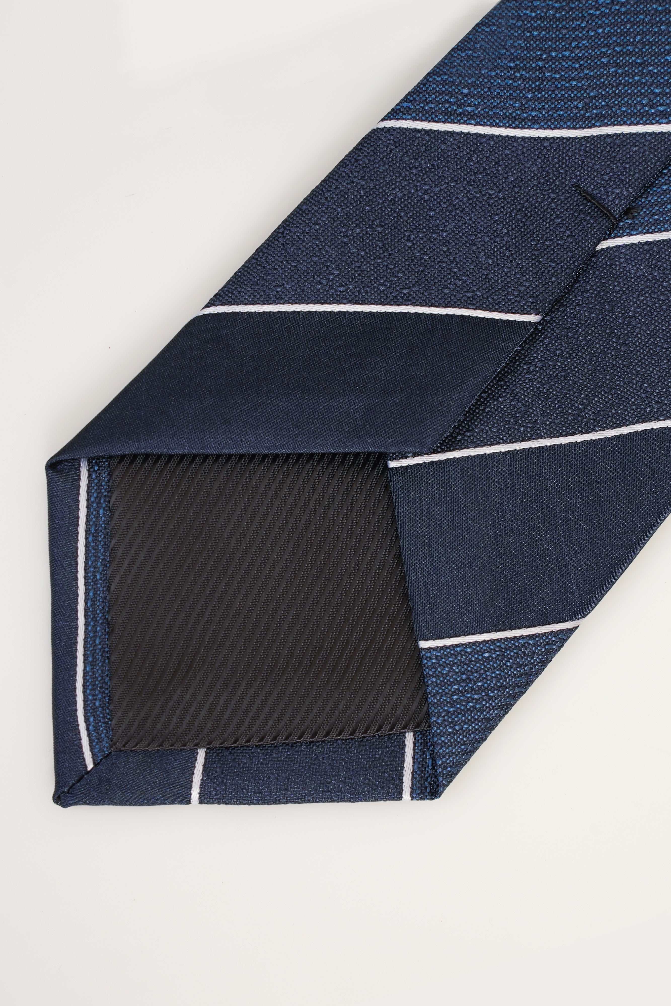 Striped tie end with navy fabric, white lines, and black fold lining
