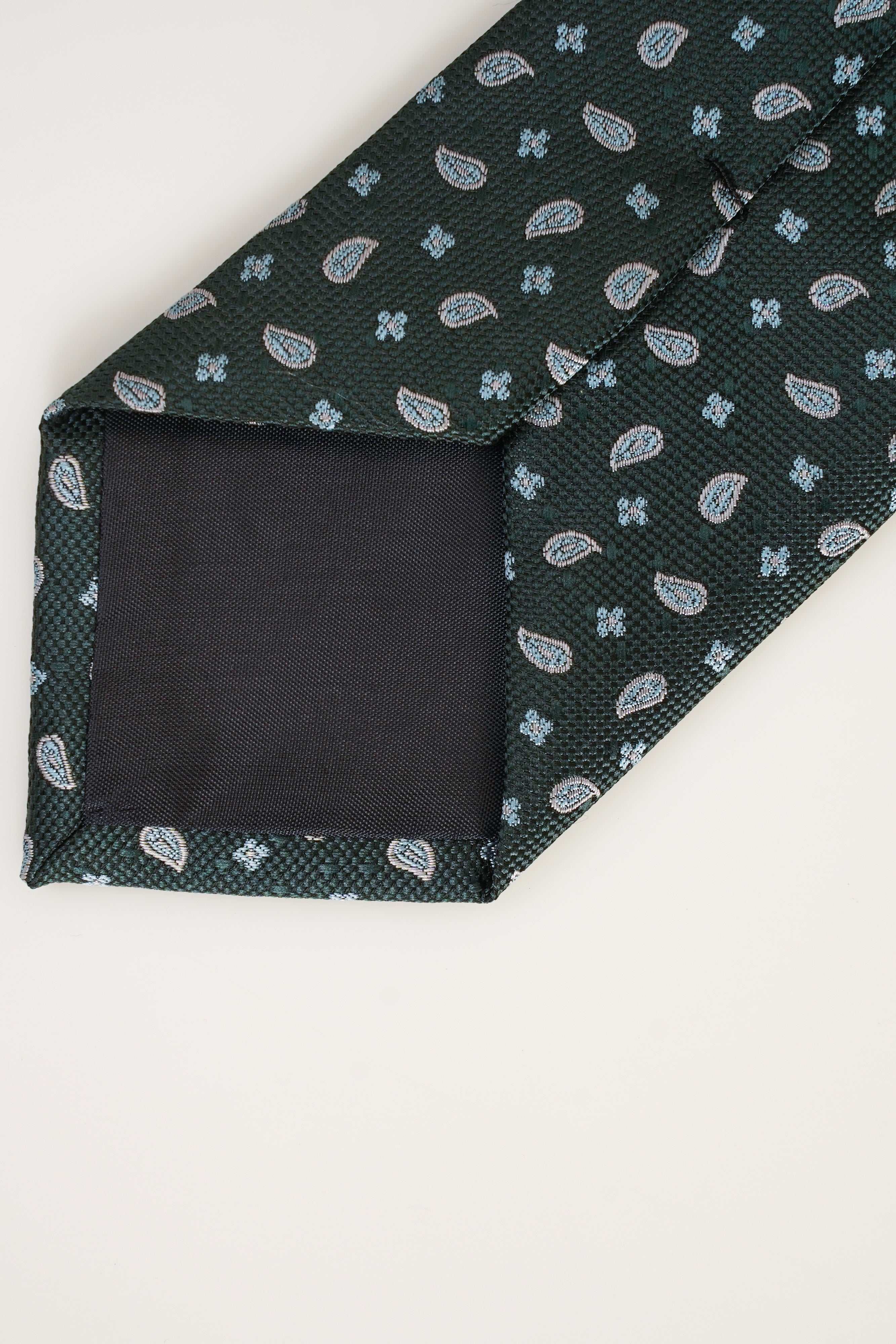 Poly silk tie end, dark teal fabric with white paisley pattern and black lining.